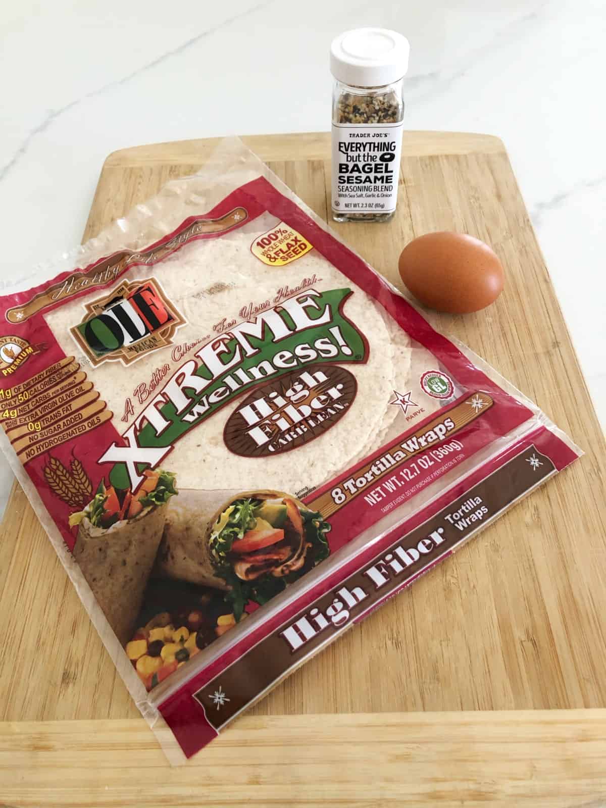 Package of high fiber, low carb tortillas on bamboo cutting board with egg and everything but the bagel seasoning