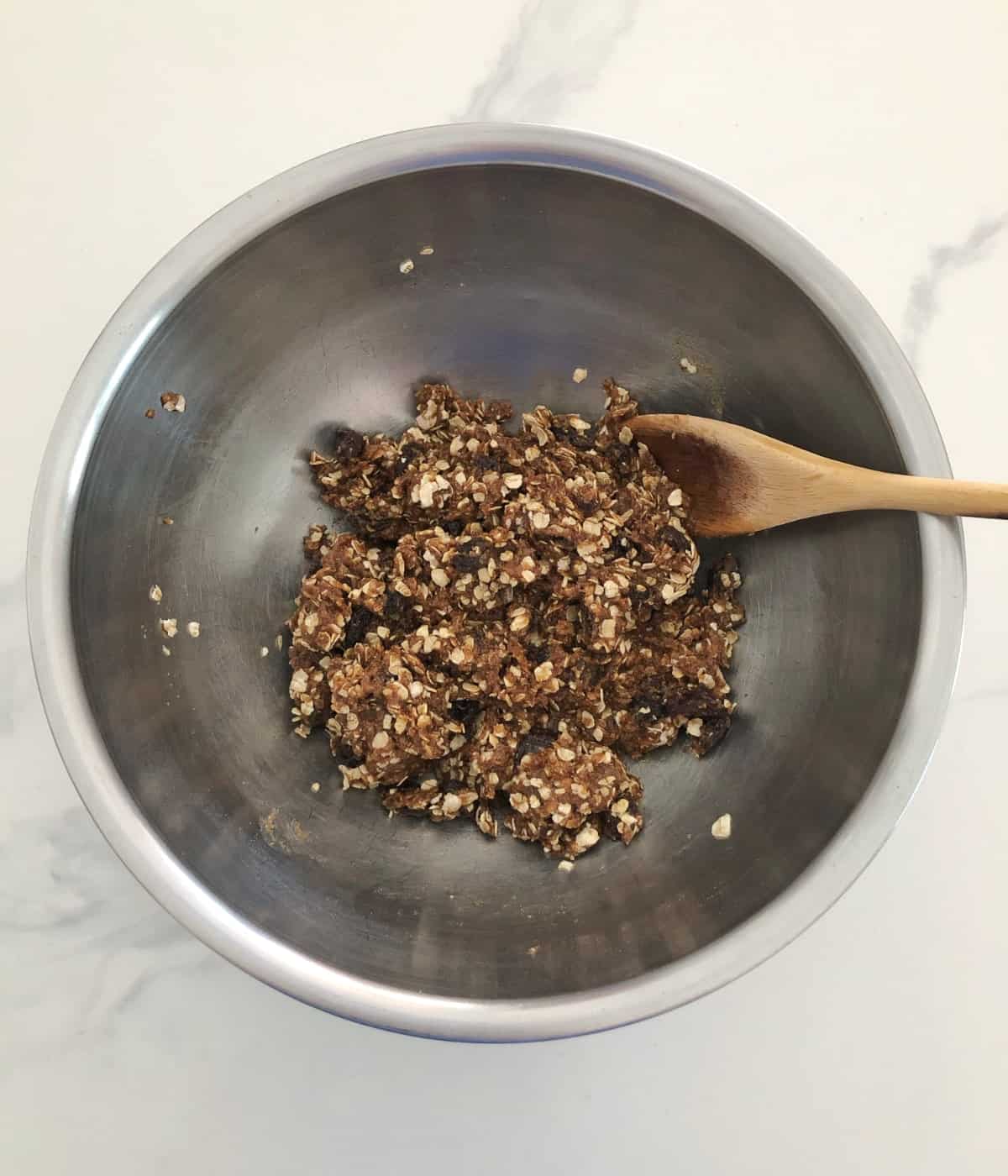 Folding oats and raisins into cookie batter with wooden spoon.
