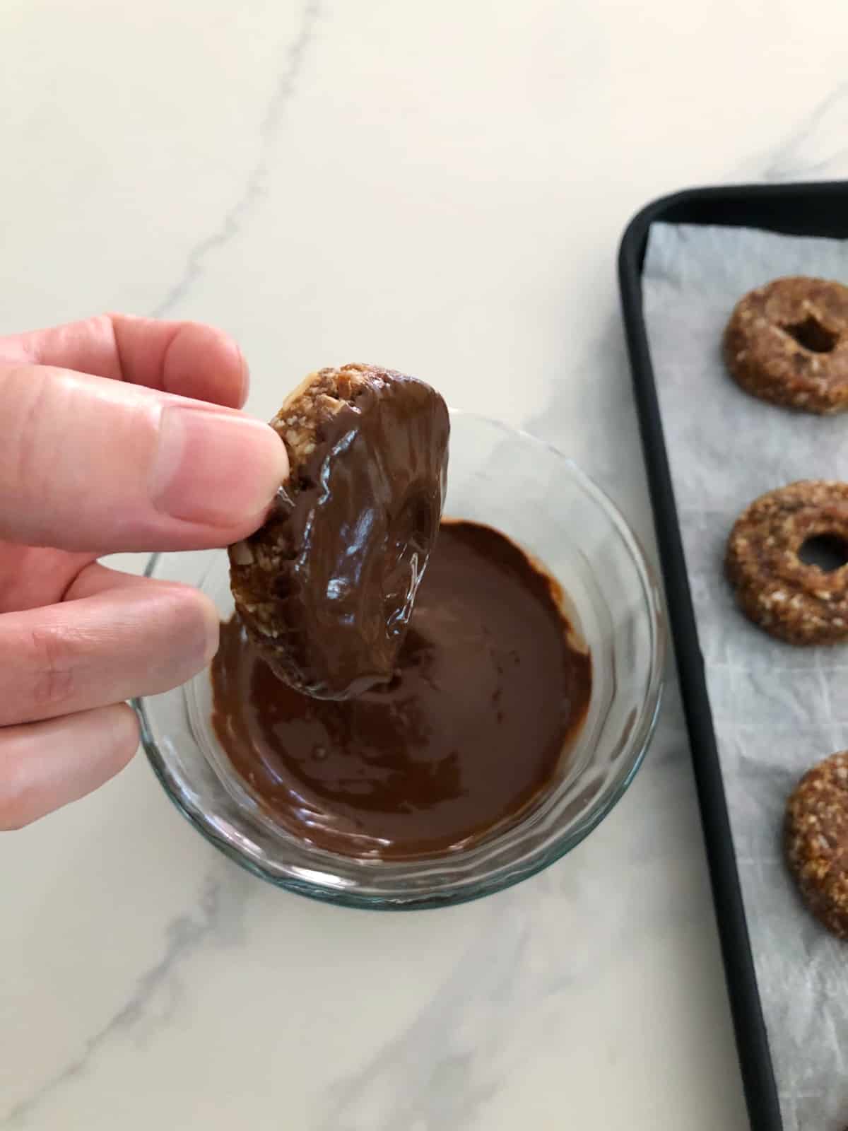 Dipping bottoms of Samoas cookies in melted chocolate.