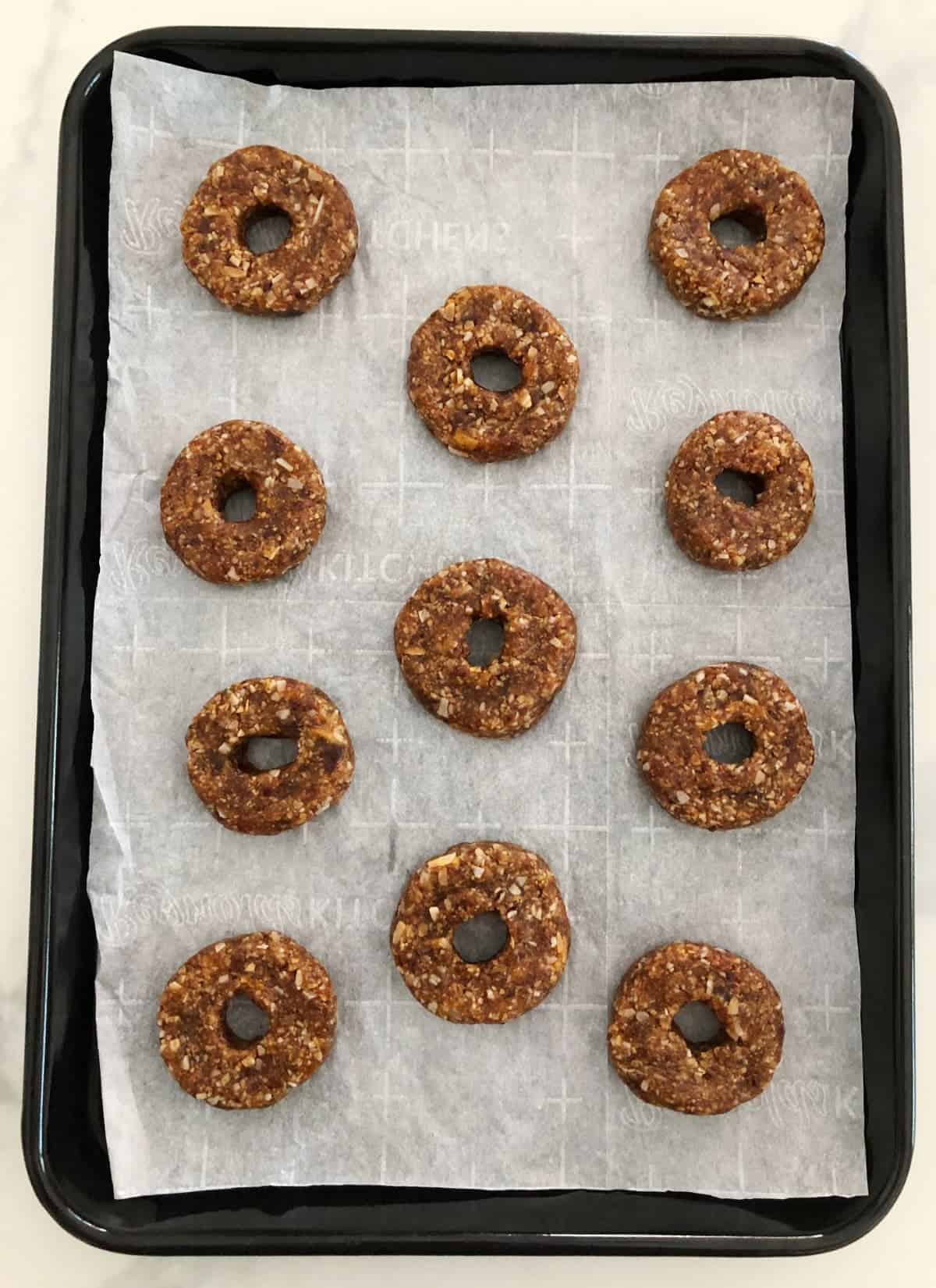 Samoas cookies before dipping in chocolate on parchment lines baking pan.