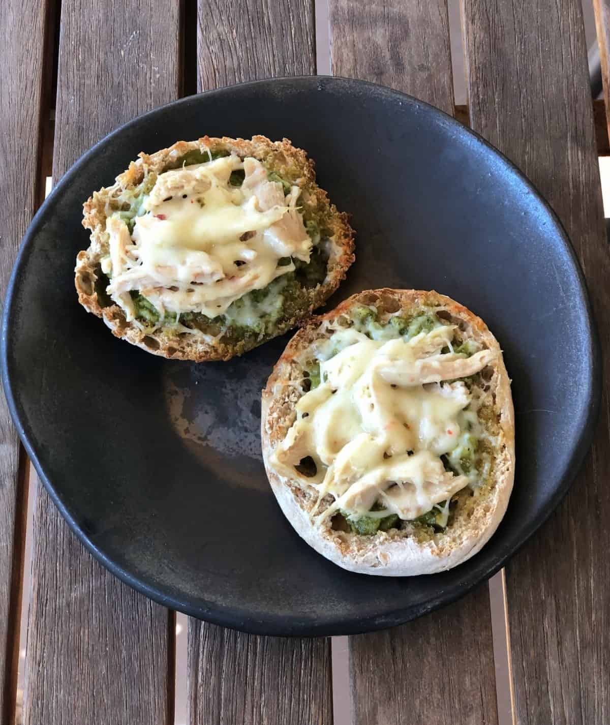English muffin spicy chicken pesto pizza on brown ceramic plate on wooden table.