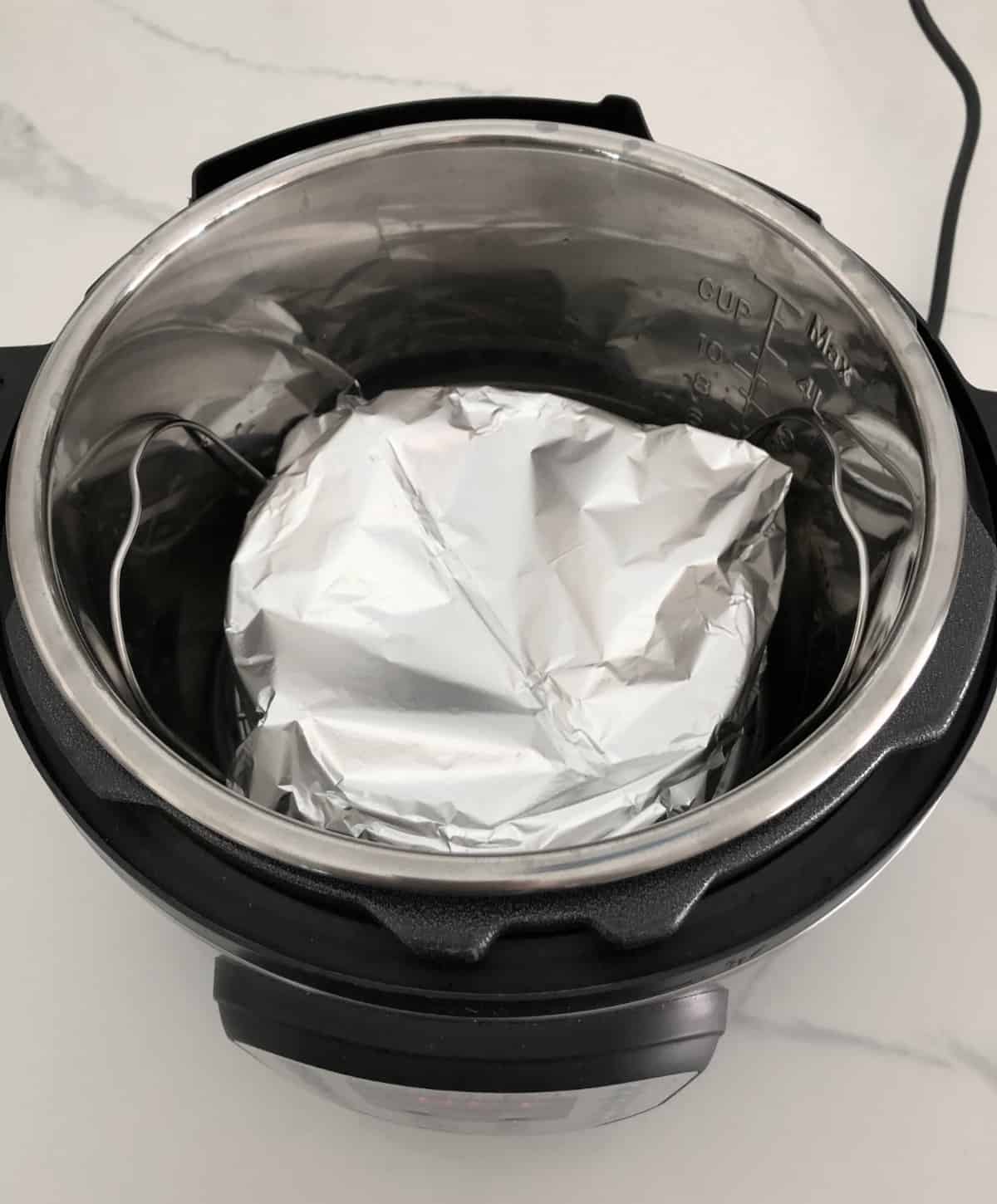 Foil-covered cake pan sitting on wire rack in InstantPot
