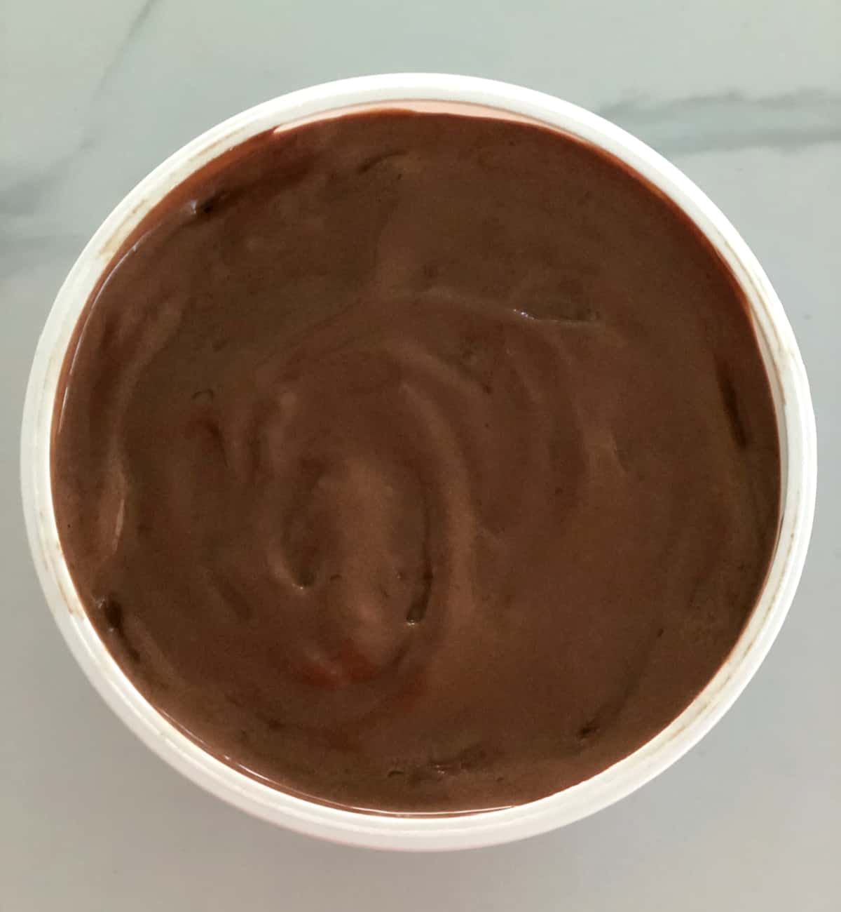 Unfrozen chocolate gelato in container from above.