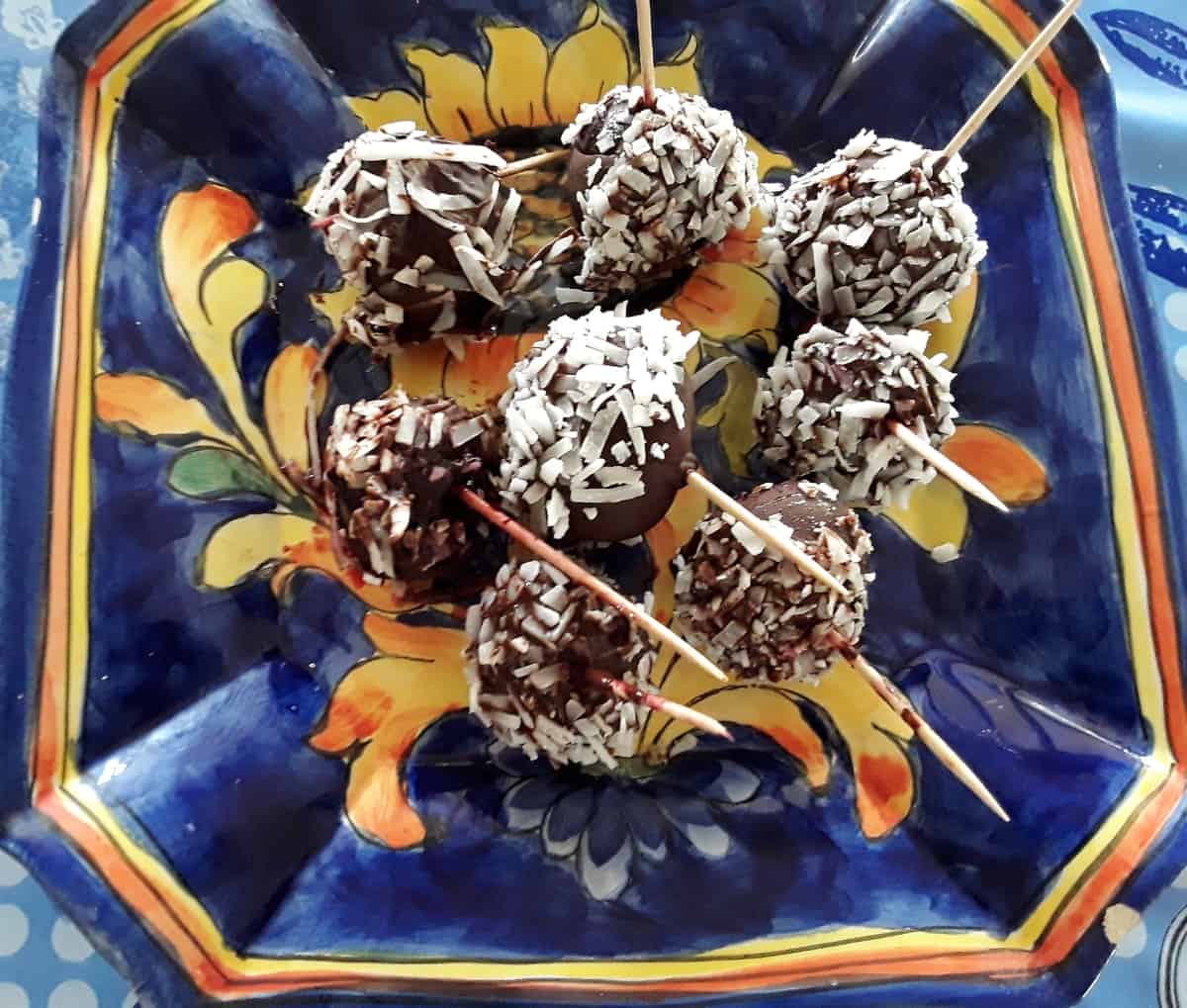 Chocolate coconut covered cherries on blue ceramic plate.