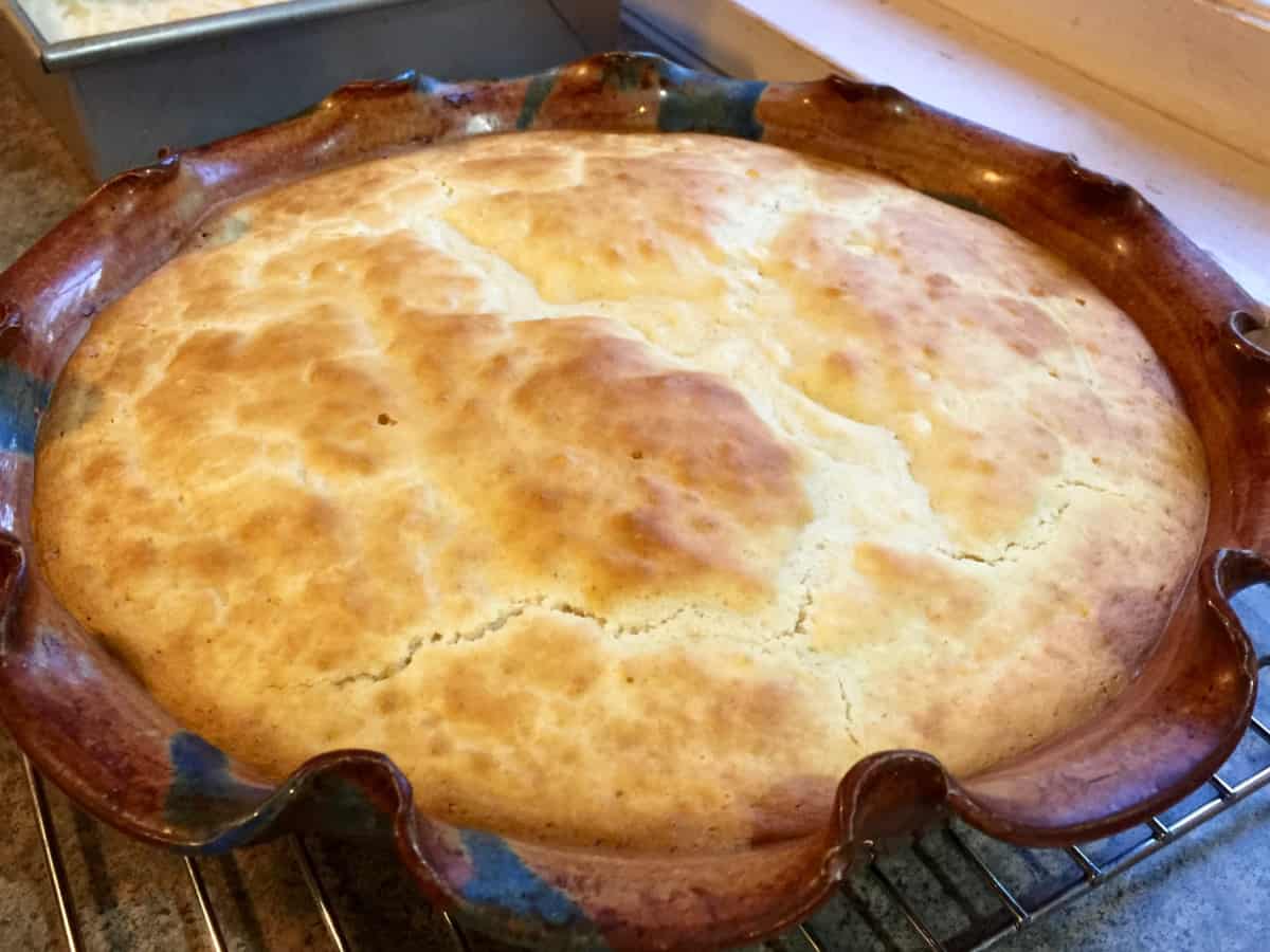 Fresh baked impossible chicken pot pie in pie dish on wire rack.
