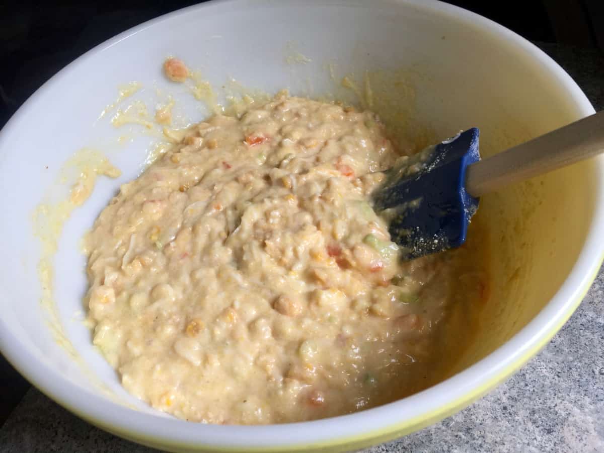 Stirring together corn casserole ingredients in mixing bowl with rubber spatula.