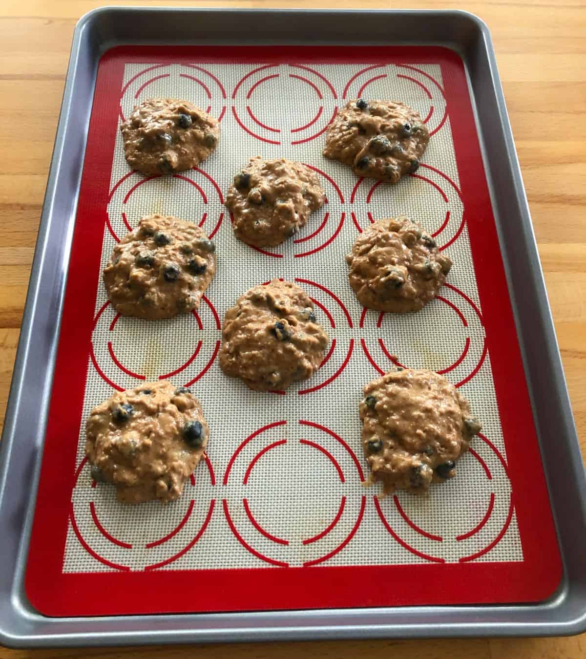 Mounds of blueberry bran muffin top batter on baking sheet.