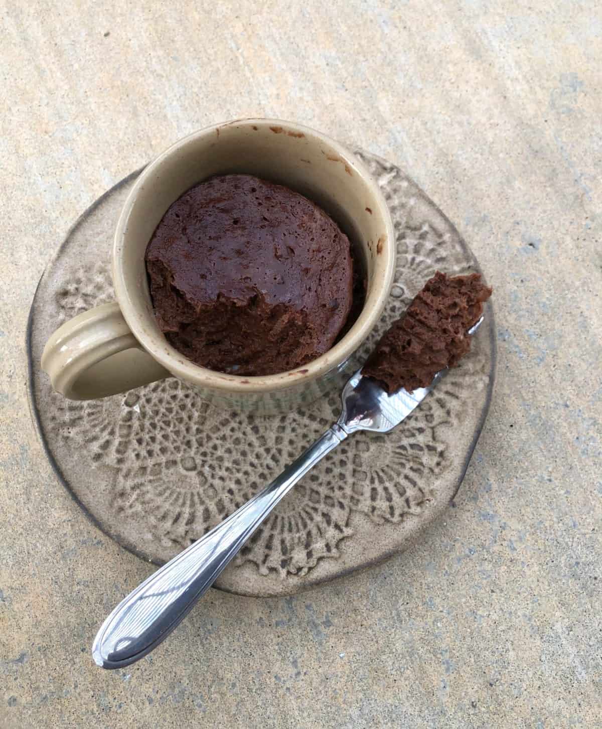 Banana cocoa mug cake on small plate with fork.