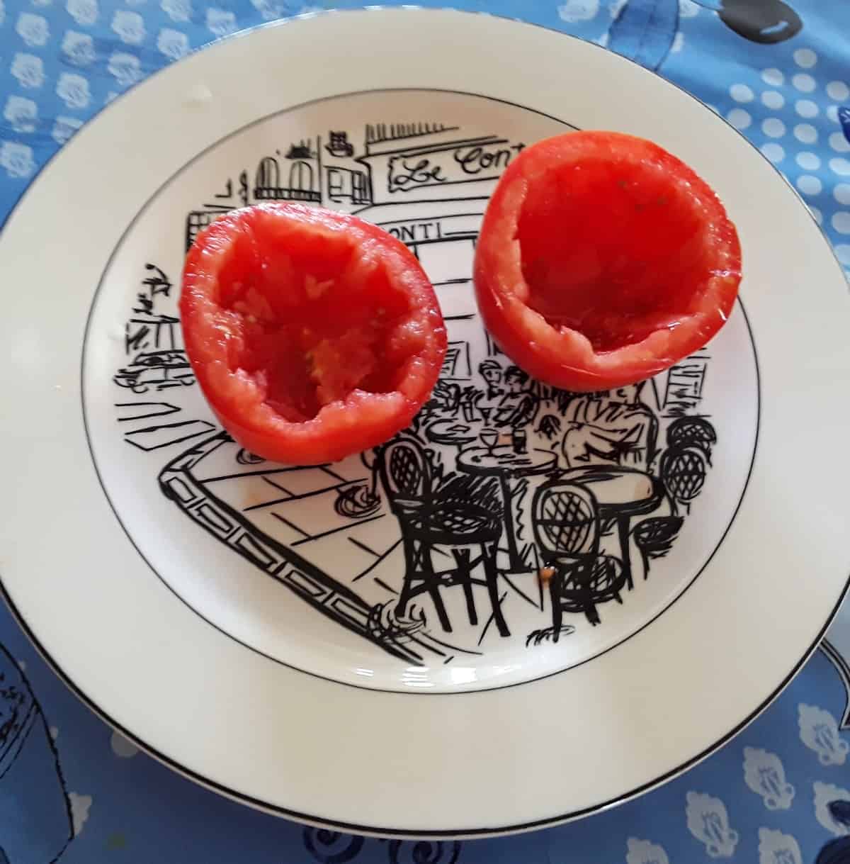 Roma tomato cut in halve and hollowed out on white plate.