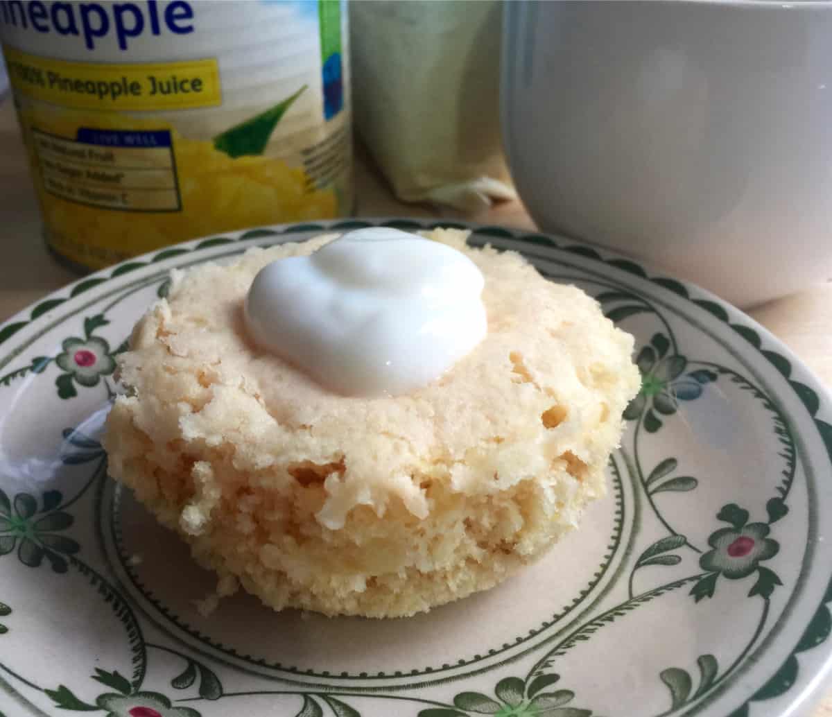 Microwave mug pineapple cake on plate topped with light whipped topping.
