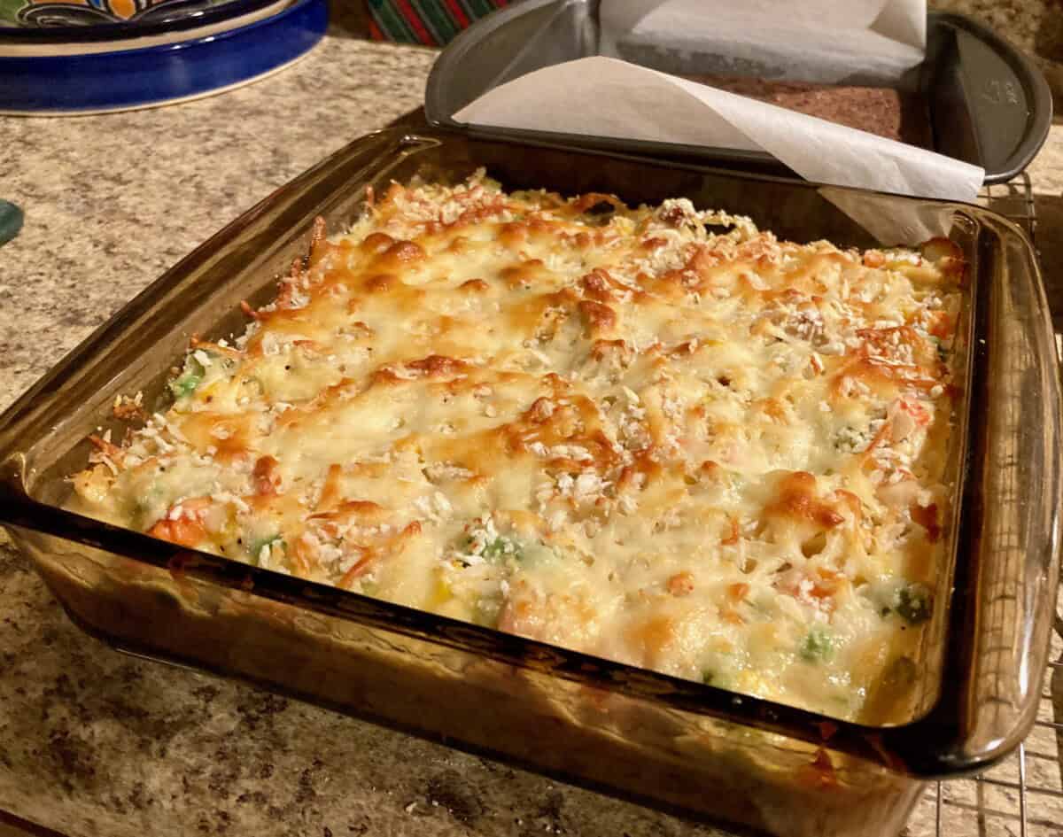 Baked chicken noodle casserole in dark pyrex dish.