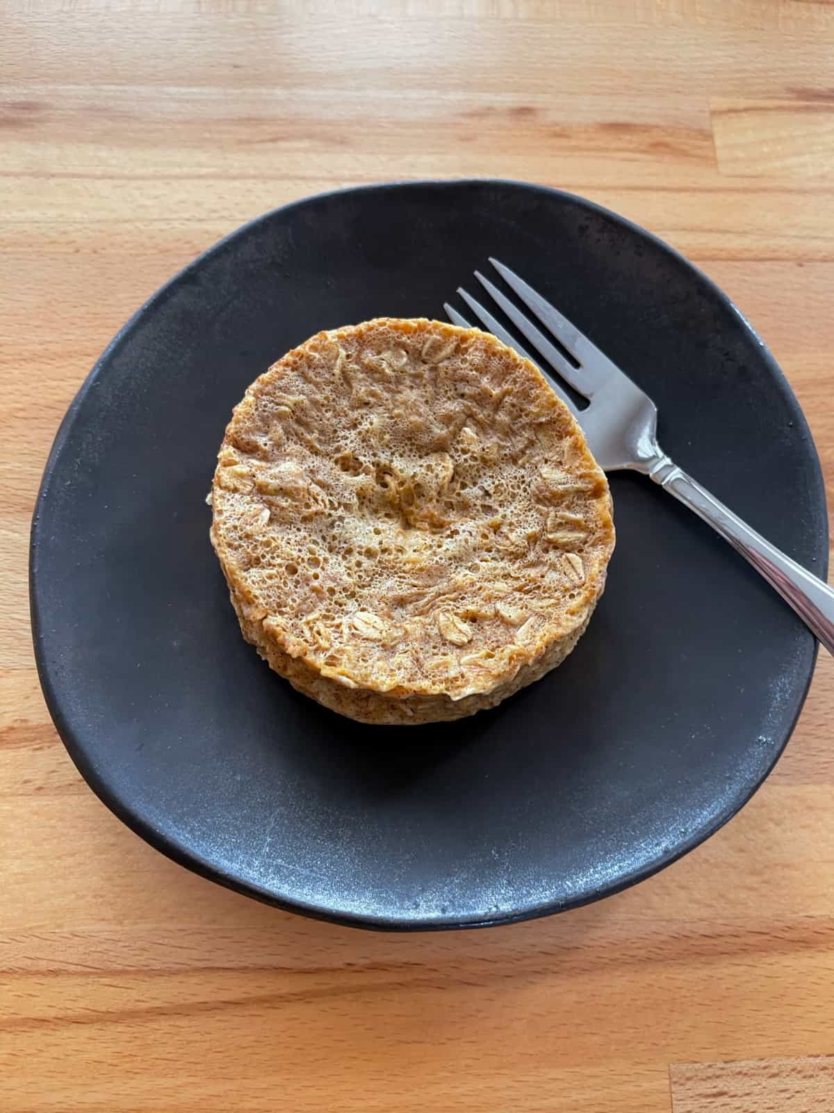 Oatmeal raisin microwave muffin on brown ceramic plate with fork.