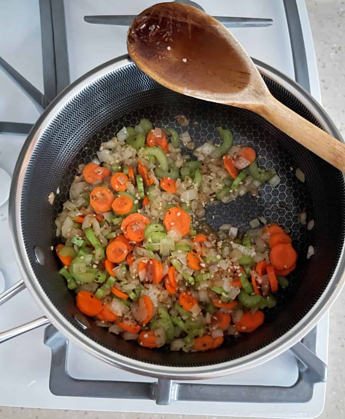 Cooking onion, celery, carrots and garlic in soup pot.