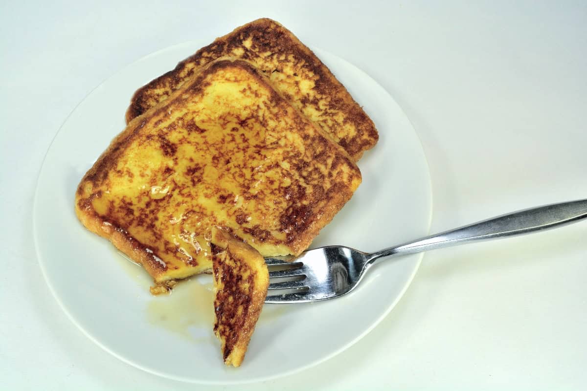 Pumpkin Pie French Toast with maple syrup on white plate with fork.