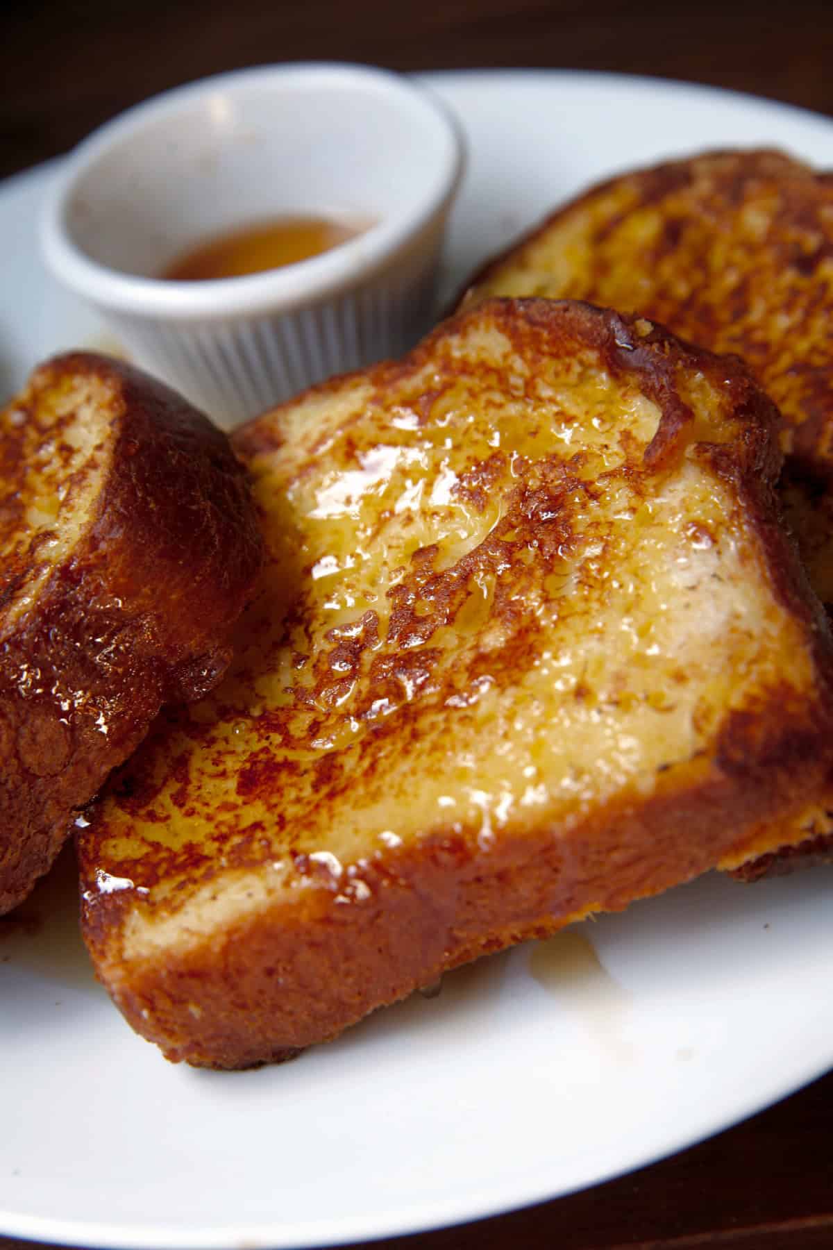 Pumpkin Pie French Toast with maple syrup on white plate.