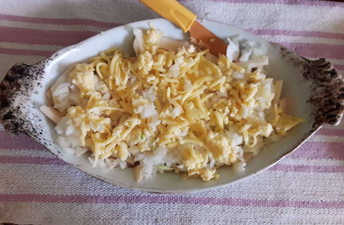Layering bacon, potato, onion and shredded cheese in casserole dish.