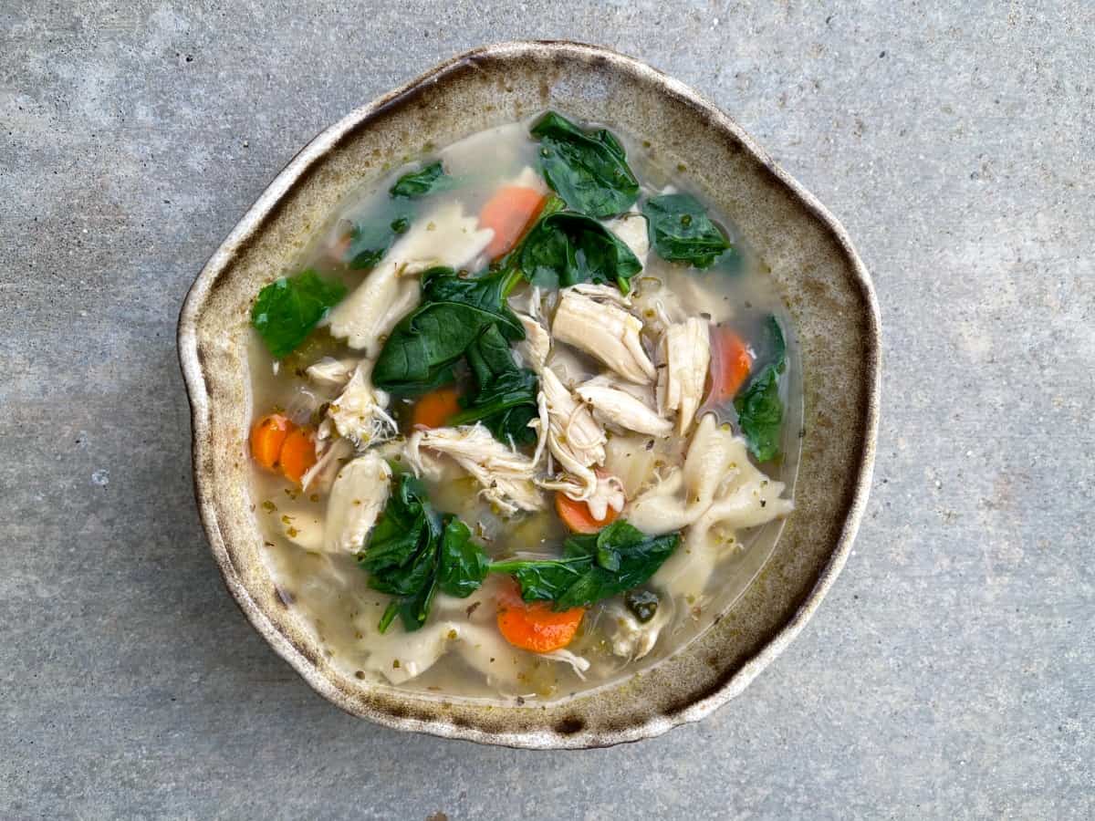 Tuscan chicken bowtie pasta soup in brown ceramic bowl from above.