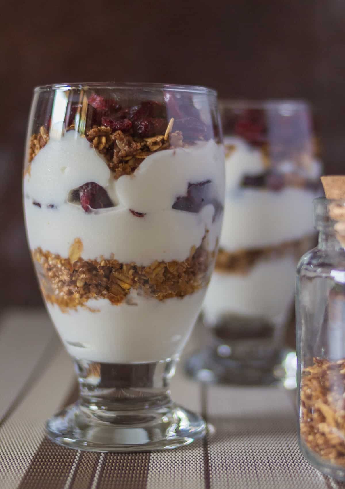 Yogurt granola fruit parfait in tall glass.