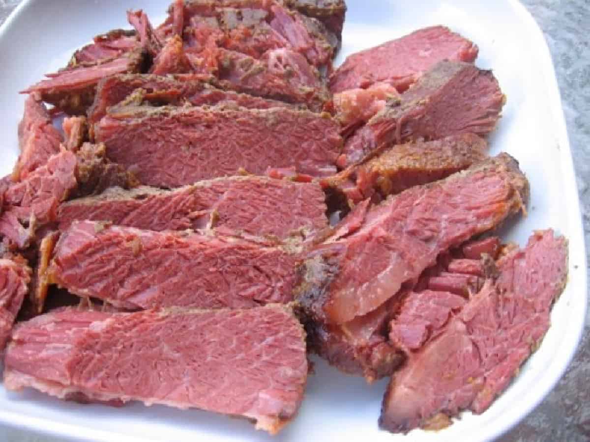 Sliced corned beef on white serving platter.