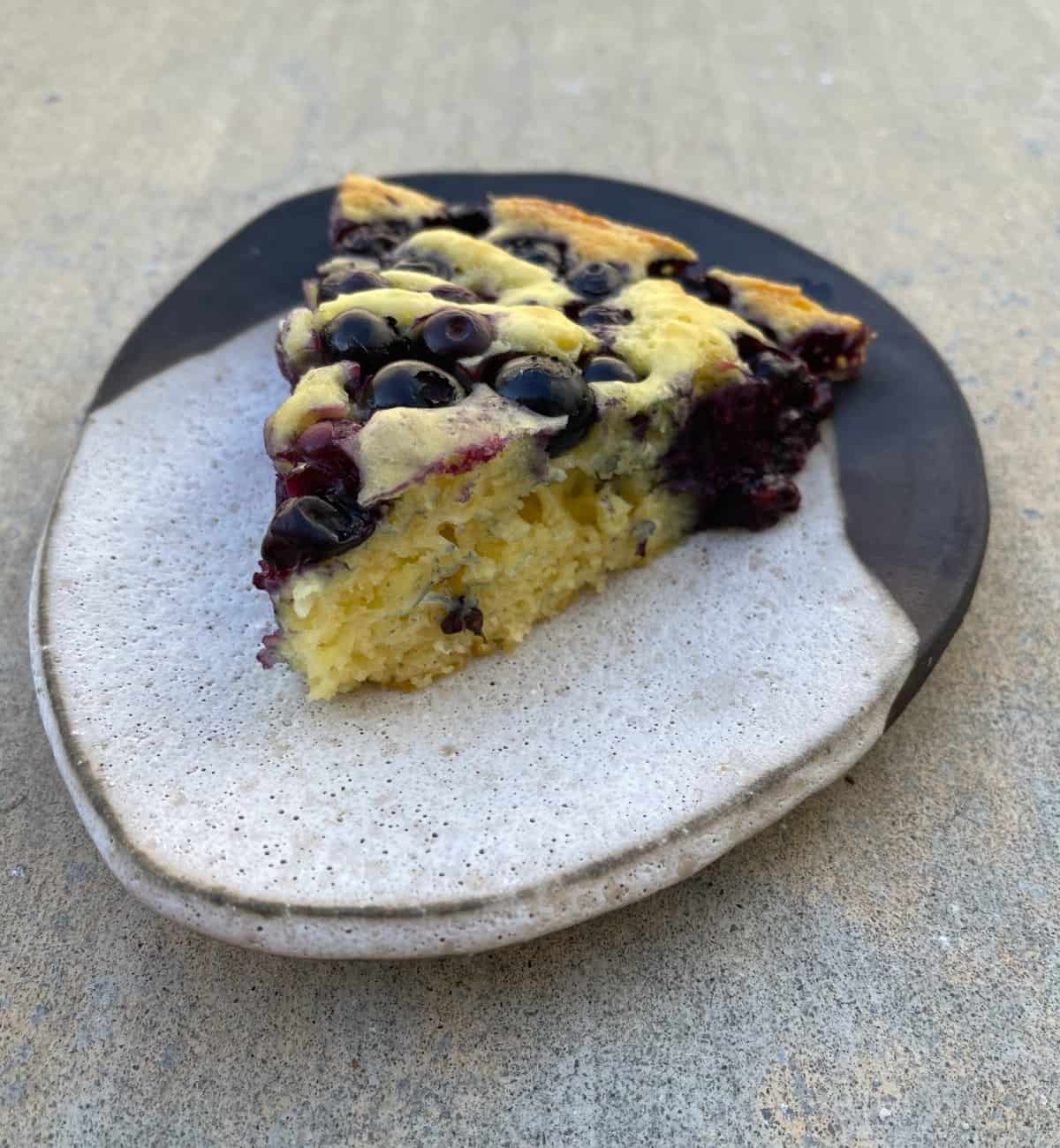Piece of blueberry oven pancake on ceramic plate.