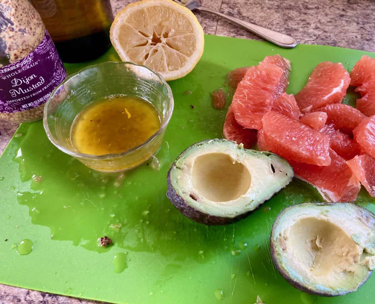 Green cutting board with avocados, grapefruits, lemon juice, mustard, olive oile