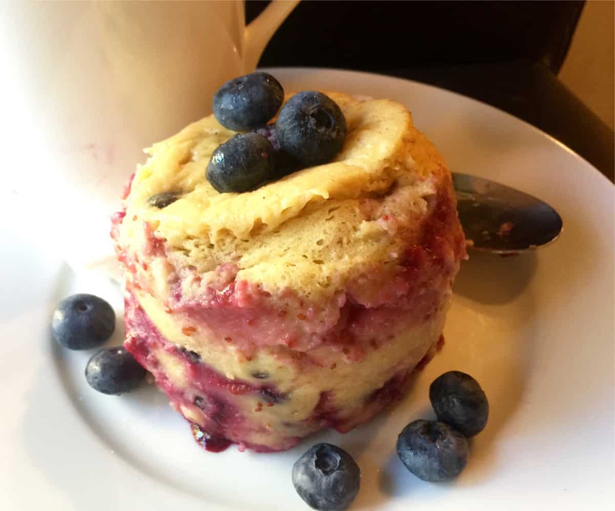 Microwave Mug Pancake with fresh blueberries on white plate.