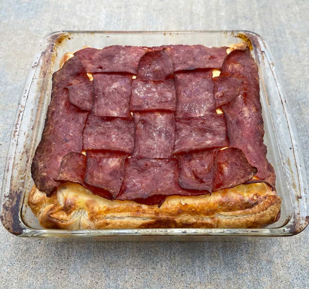 Fresh baked bacon, egg and cheese breakfast pie in glass baking dish outside.