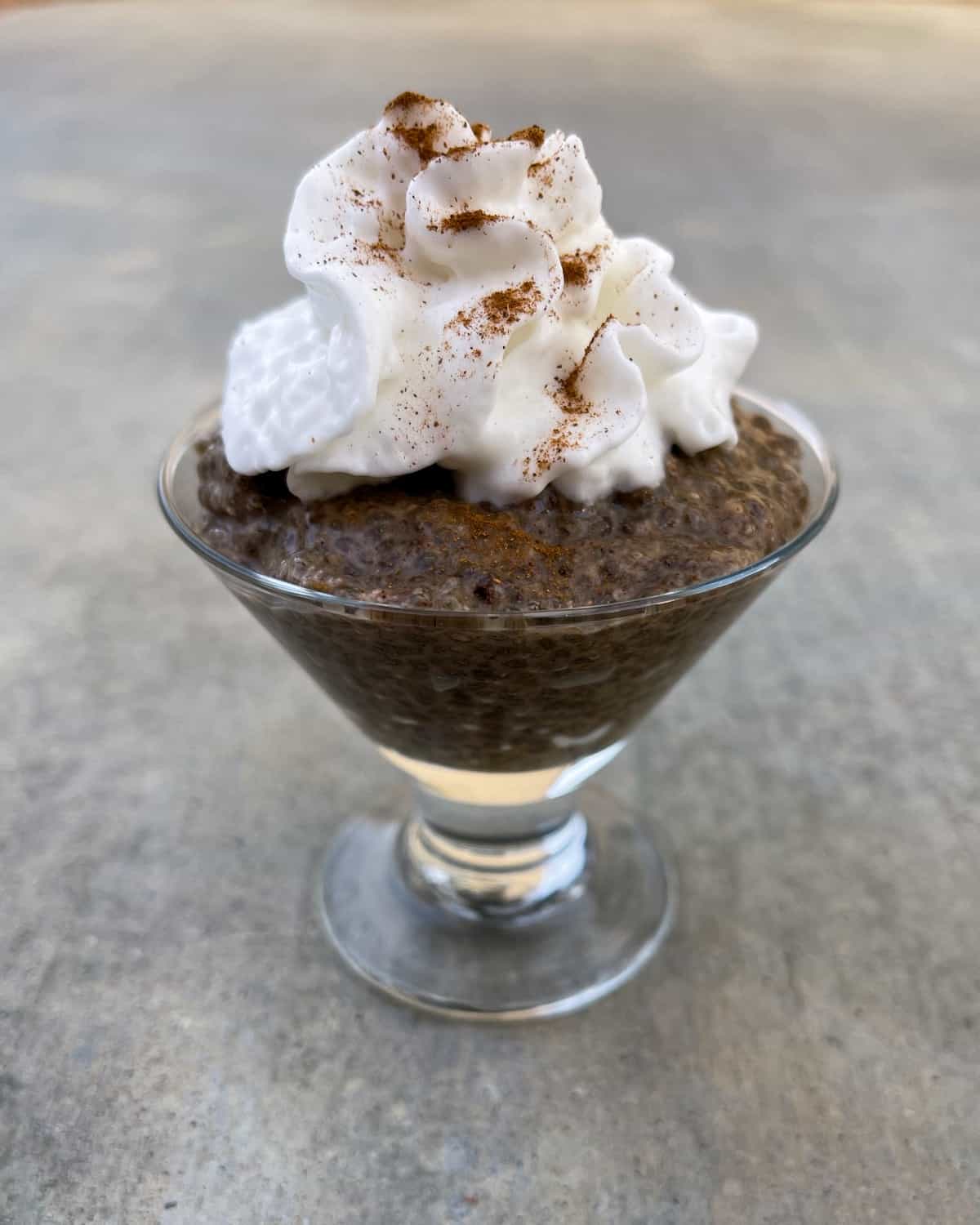 Cappuccino chia seed pudding in dessert glass with whipped cream.