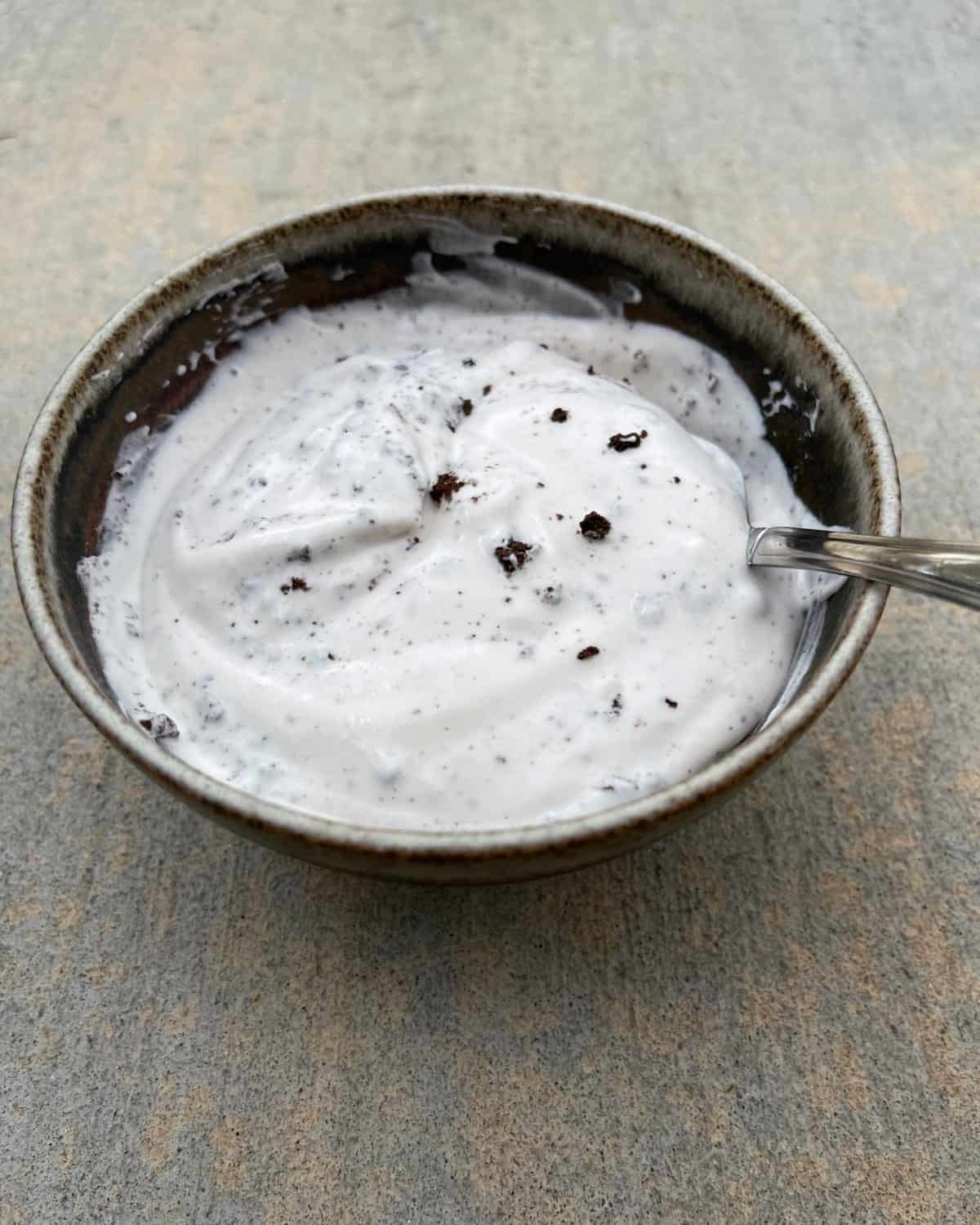 Stirring cookies and cream dip in small bowl with spoon.