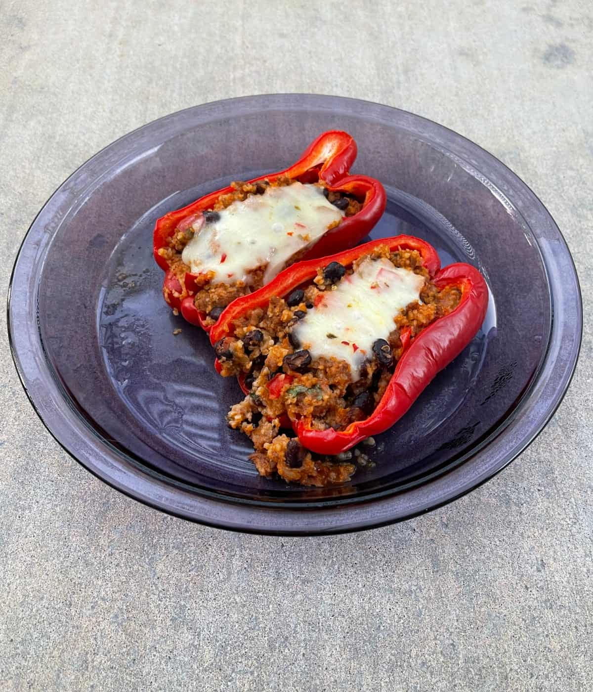 Taco casserole stuffed red peppers in glass pie dish.