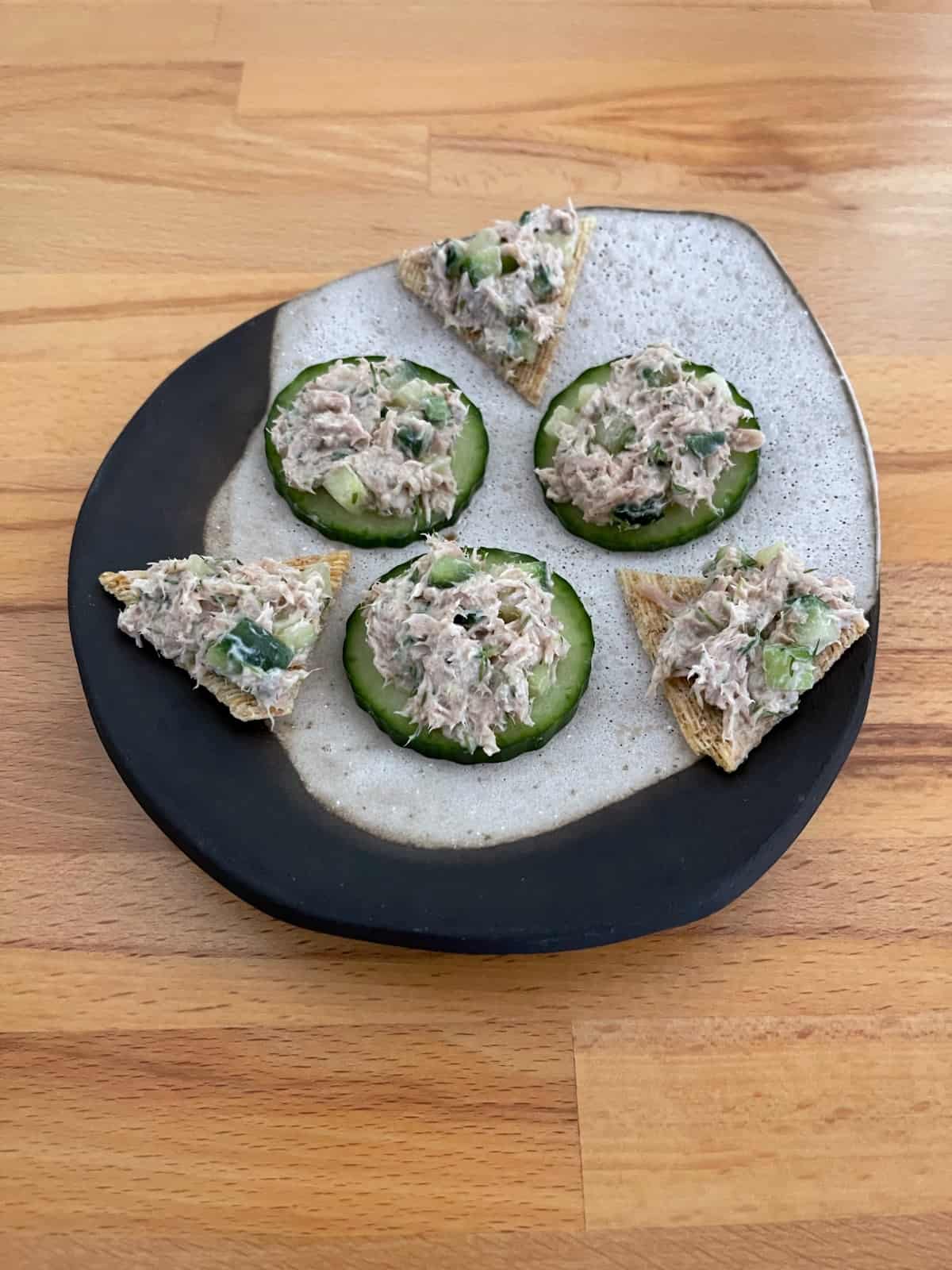 Dilly tuna spread on cucumber slices and Triscuit thin crisps on ceramic plate.