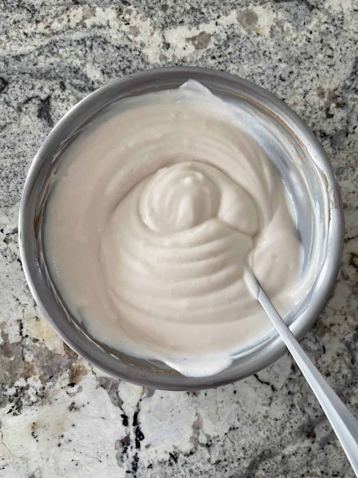 Stirring Greek yogurt, truvia and vanilla in mixing bowl with spoon.