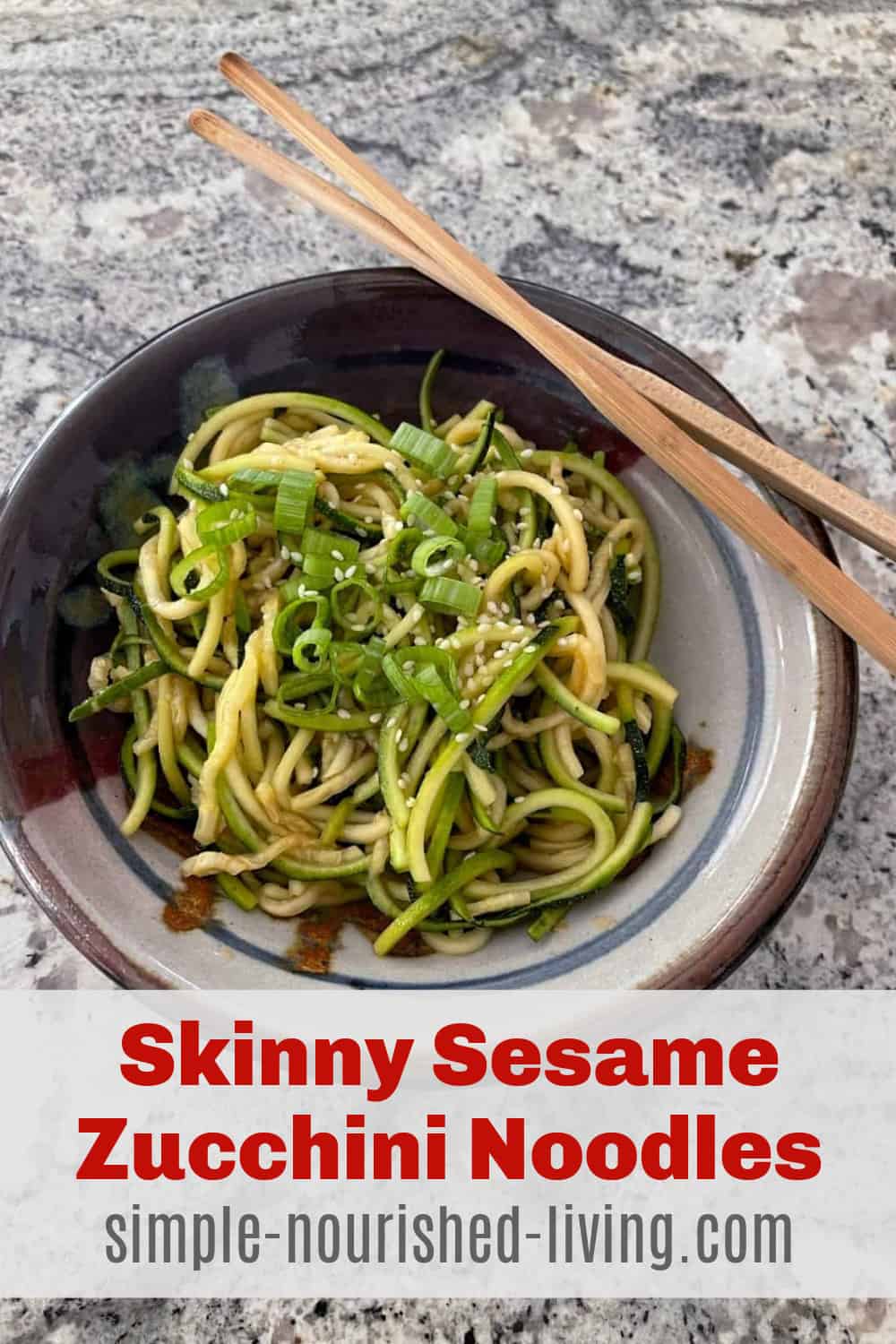 pottery bowl filled with skinny sesame zucchini noodles on granite countertop. Chopsticks balancing on right side of bowl.