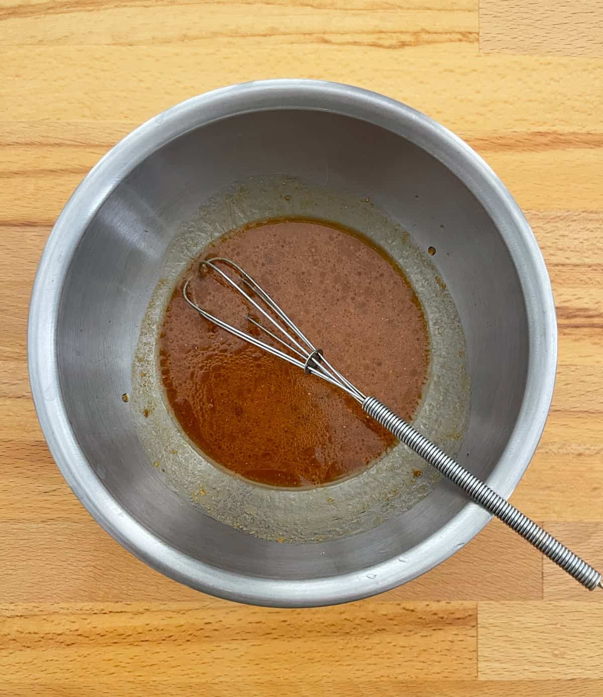Whisking soy sauce, rice vinegar, sesame oil, peanut butter powder, garlic and ginger in mixing bowl.