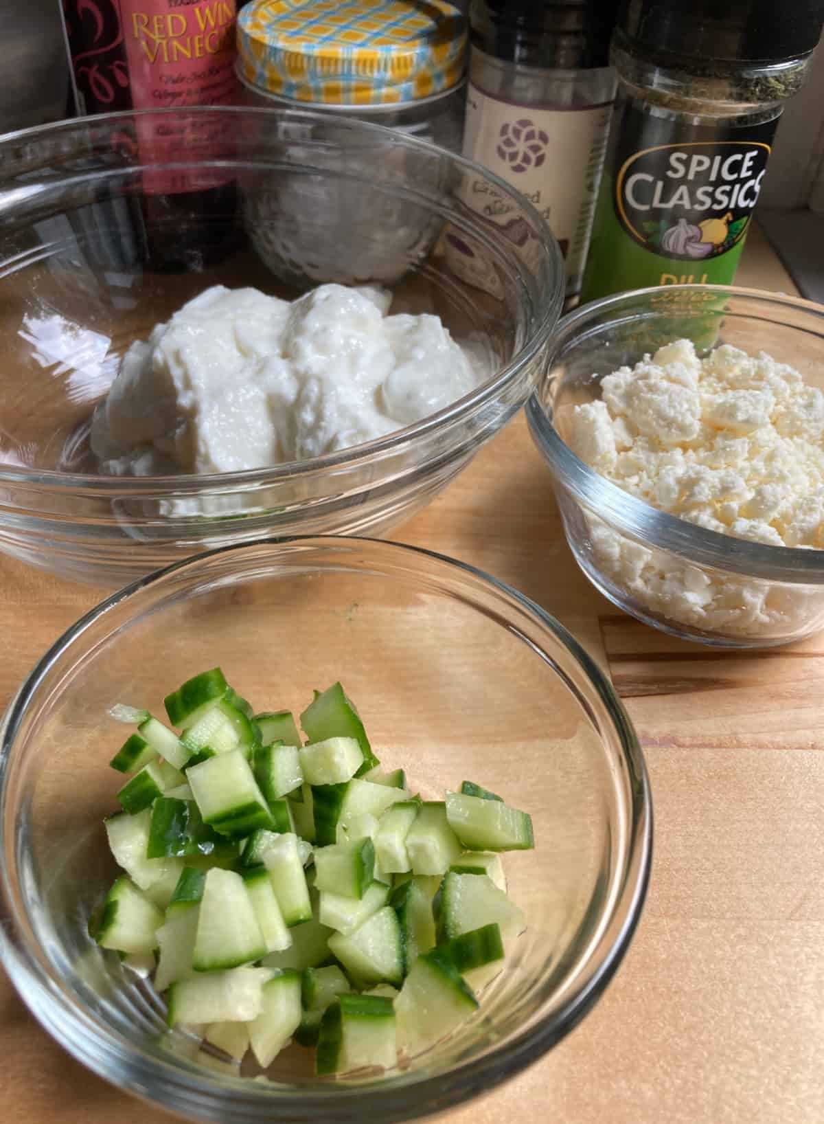 Ingredients for making salad dressing, including chopped cucumbers, feta, Greek yogurt and spices.