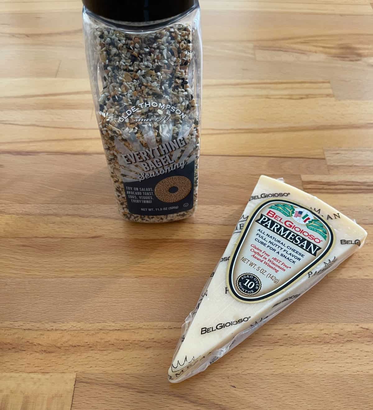 Everything Bagel seasoning and Parmesan cheese wedge on wooden table.