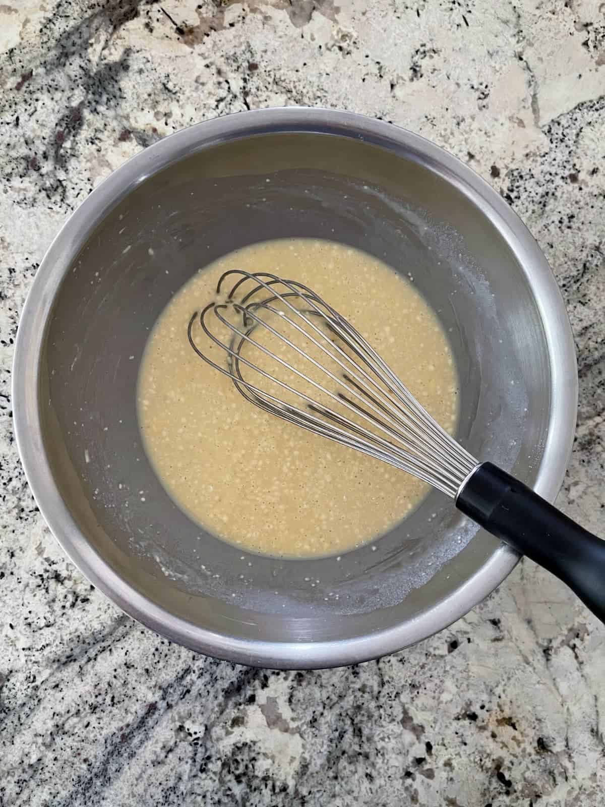 Whisking Bisquick baking mix, milk, eggs, salt and pepper in mixing bowl on granite counter.