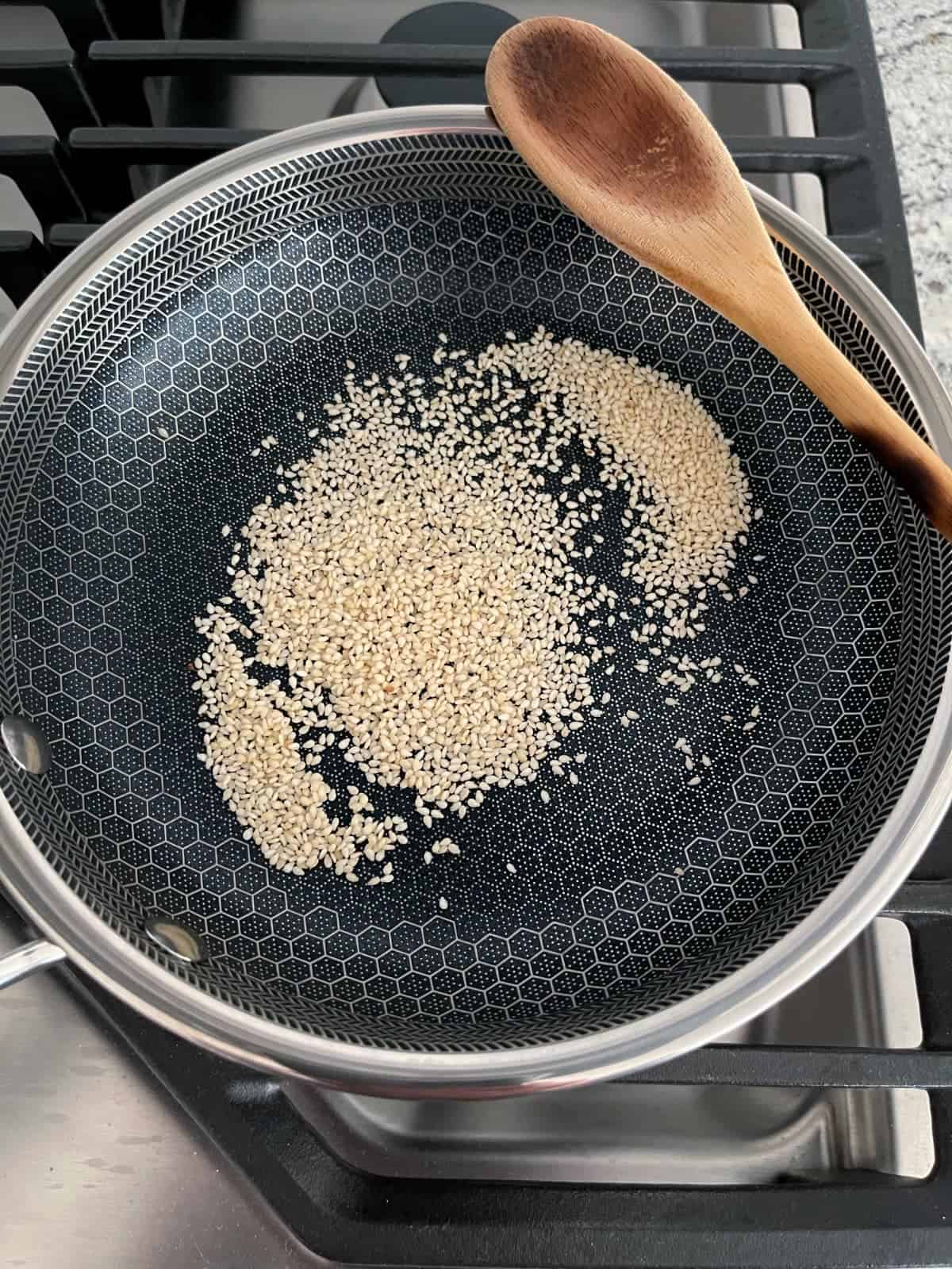 Toasting sesame seeds in small skillet on stovetop.
