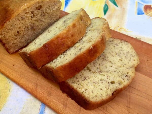Thick Slices of banana bread on cutting board on top of colorful tablecloth