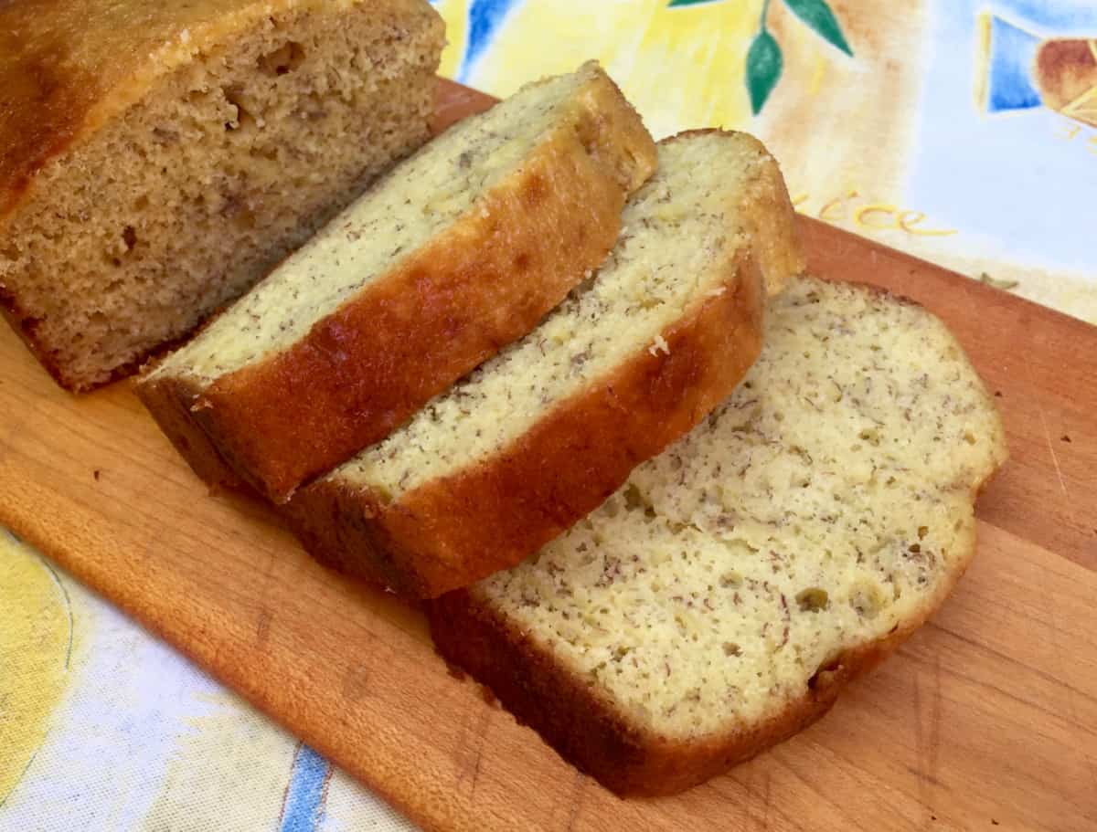 Thick Slices of banana bread on cutting board on top of colorful tablecloth