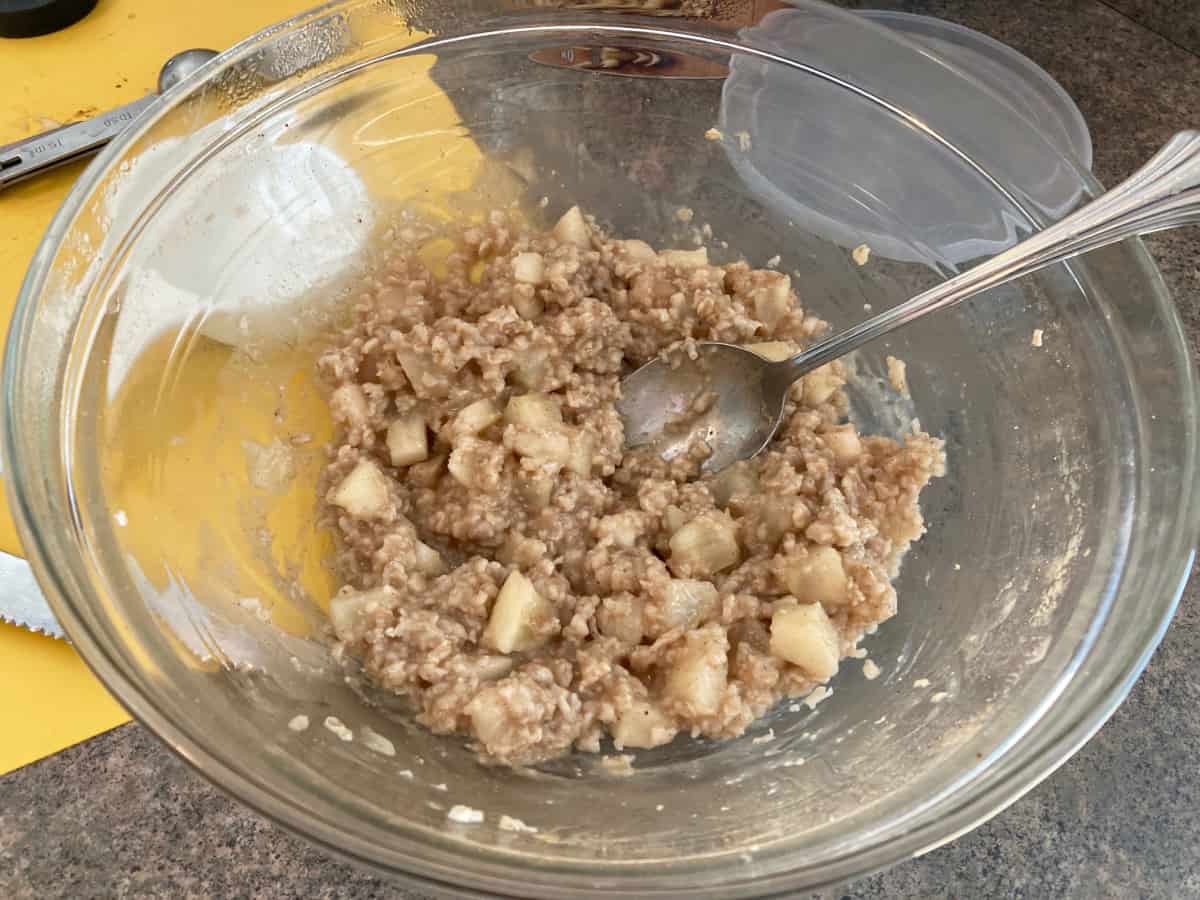 Stirring bowl of microwave apple pie oatmeal with spoon.