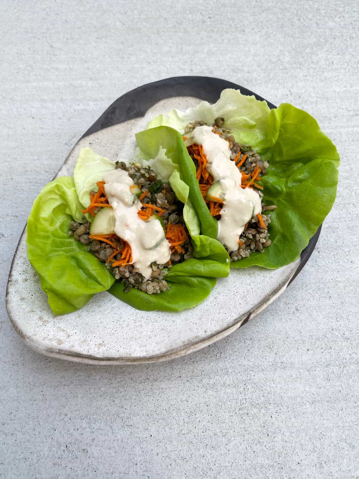 Mediterranean lettuce wraps with lentils and quinoa on ceramic plate.