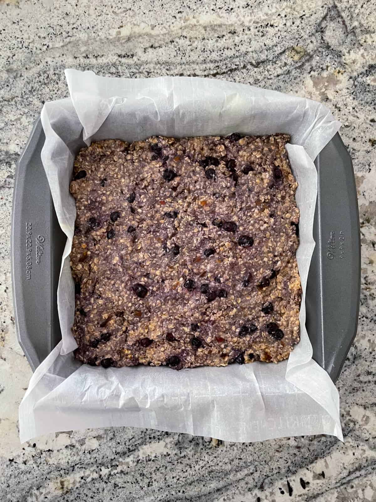 Unbaked blueberry banana oat squares in 8-inch square baking pan on granite counter.