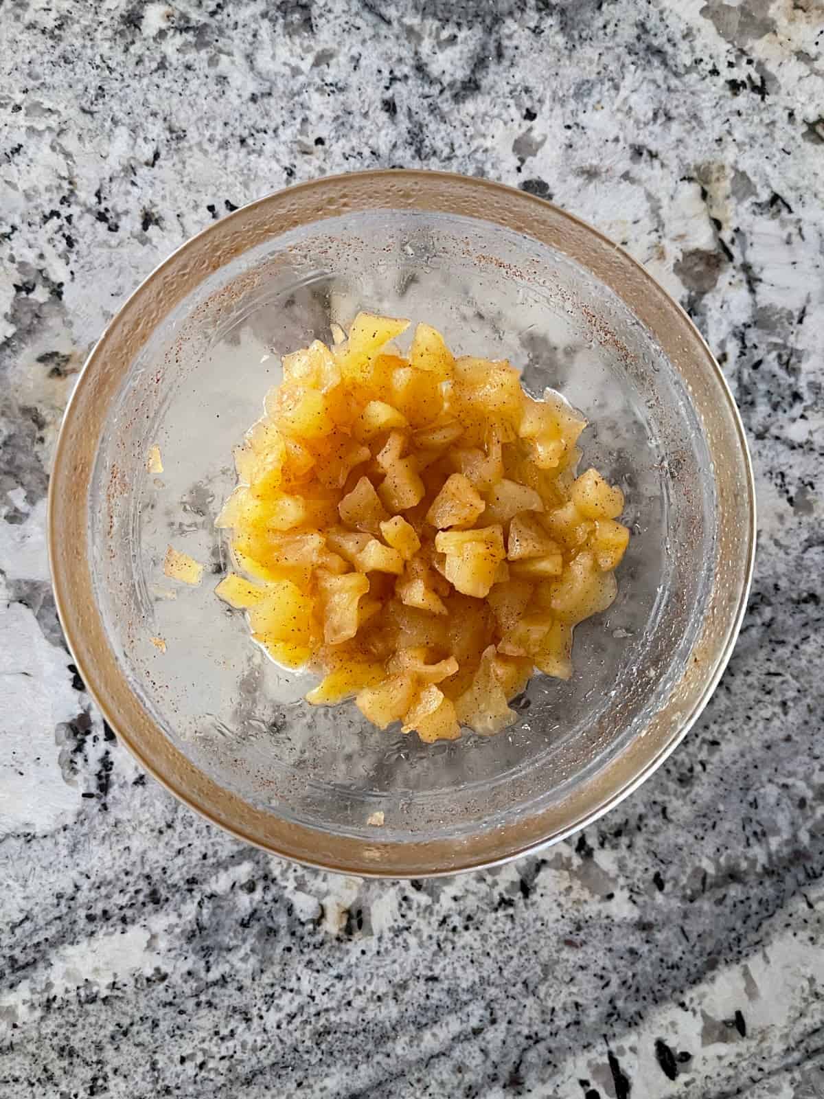 Microwave apple crisp filling in small glass bowl on granite.