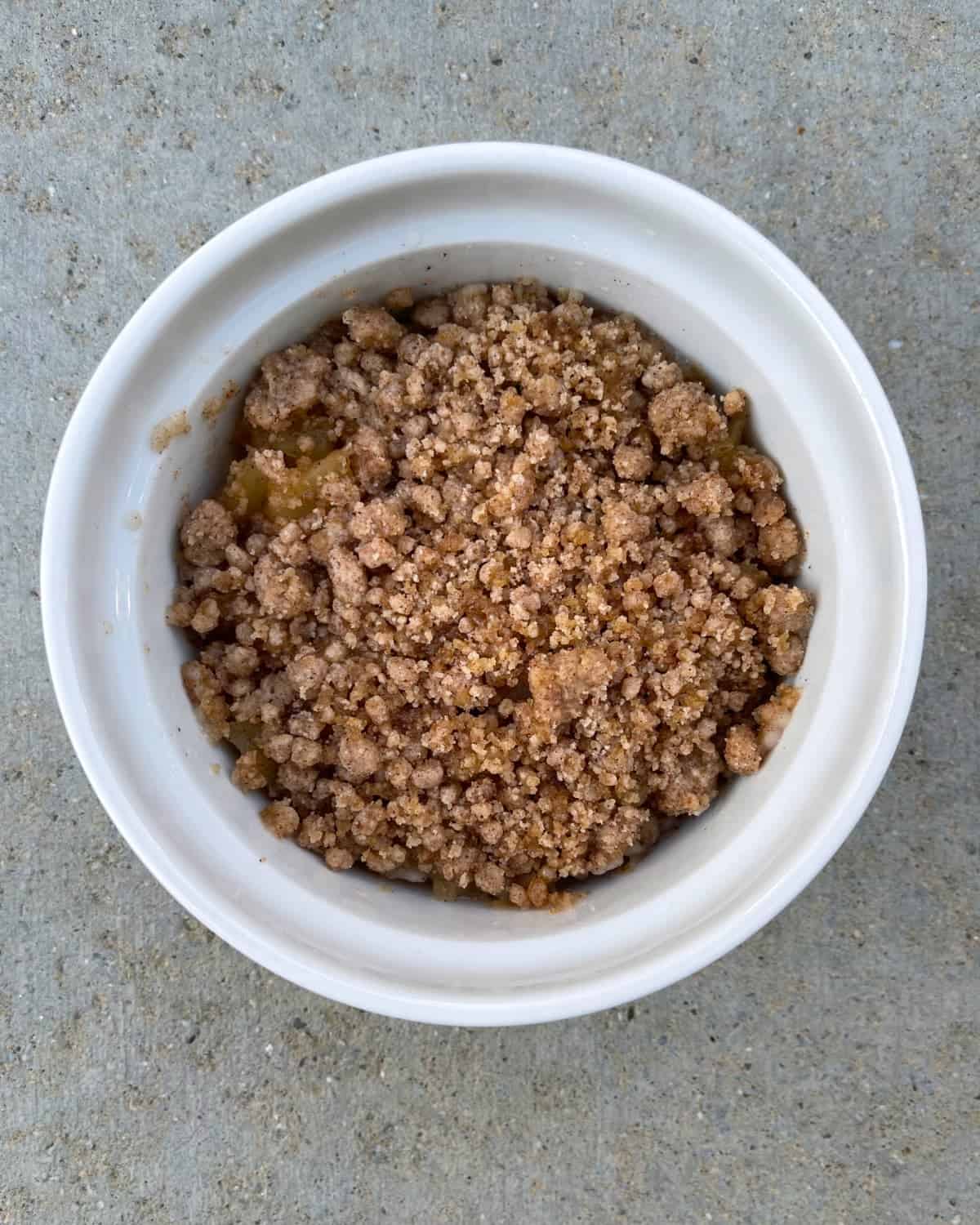 Microwave apple crisp in white ramekin without topping.