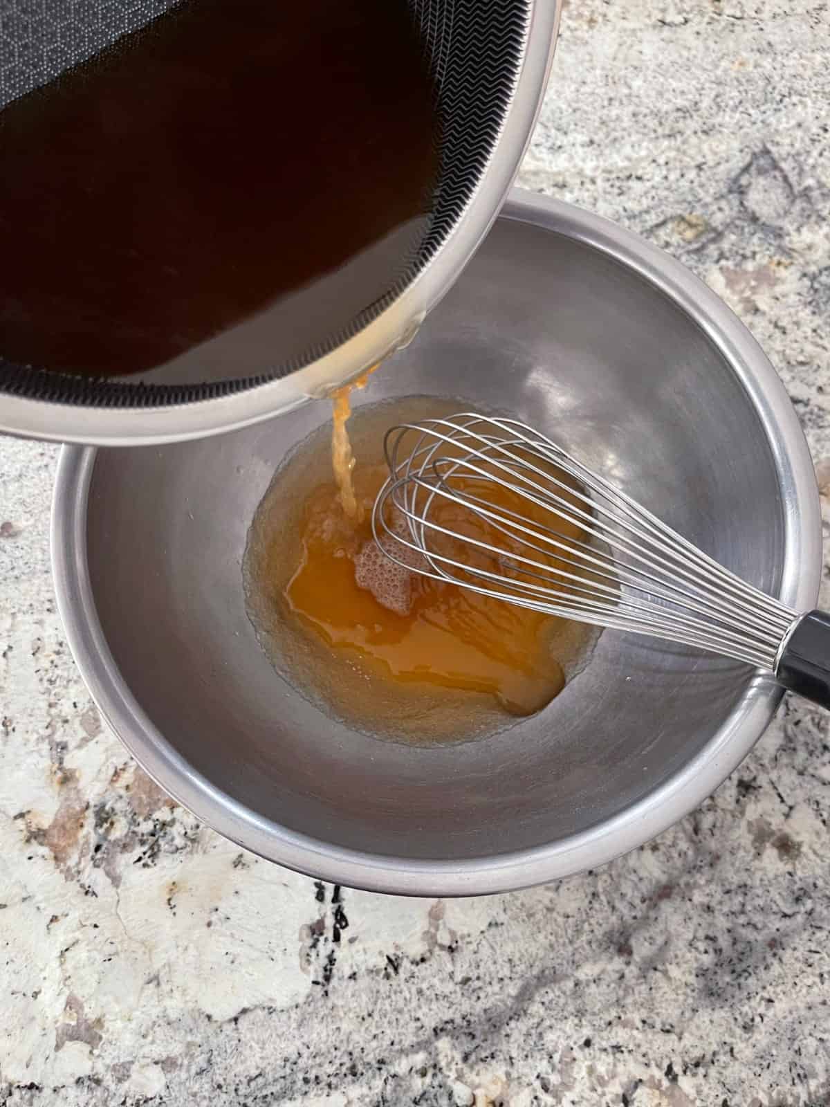 Whisking apple juice, apple cider vinegar and honey from saucepan into mixing bowl with gelatin and apple juice.