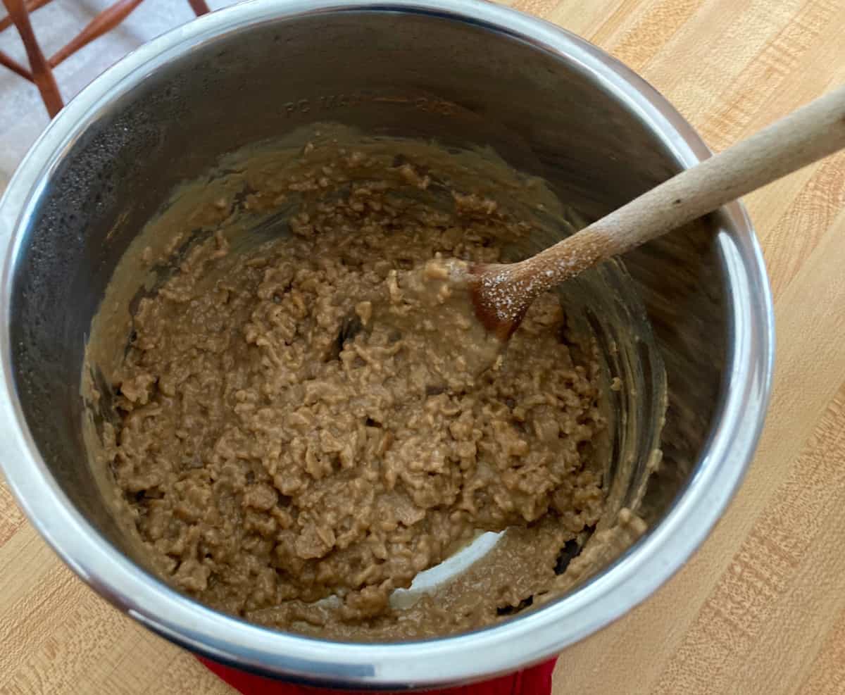 Saucepan with cooked oatmeal and wooden spoon.