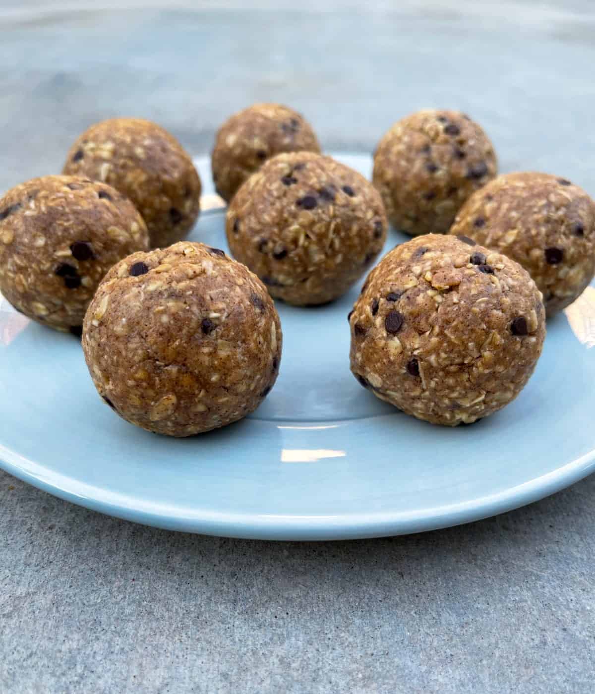 Easy no-bake oatmeal chocolate chip protein bites on blue plate up close.