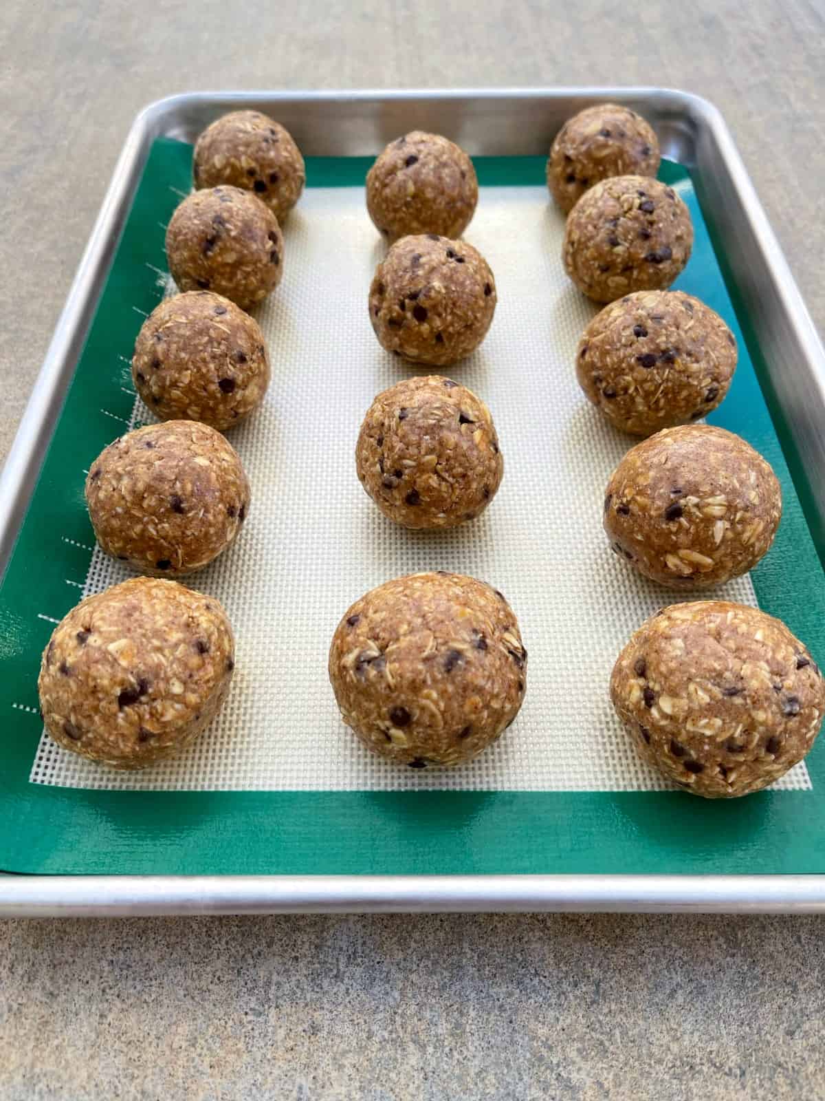 No-bake oatmeal chocolate chip protein balls in silicone-lined baking sheet.