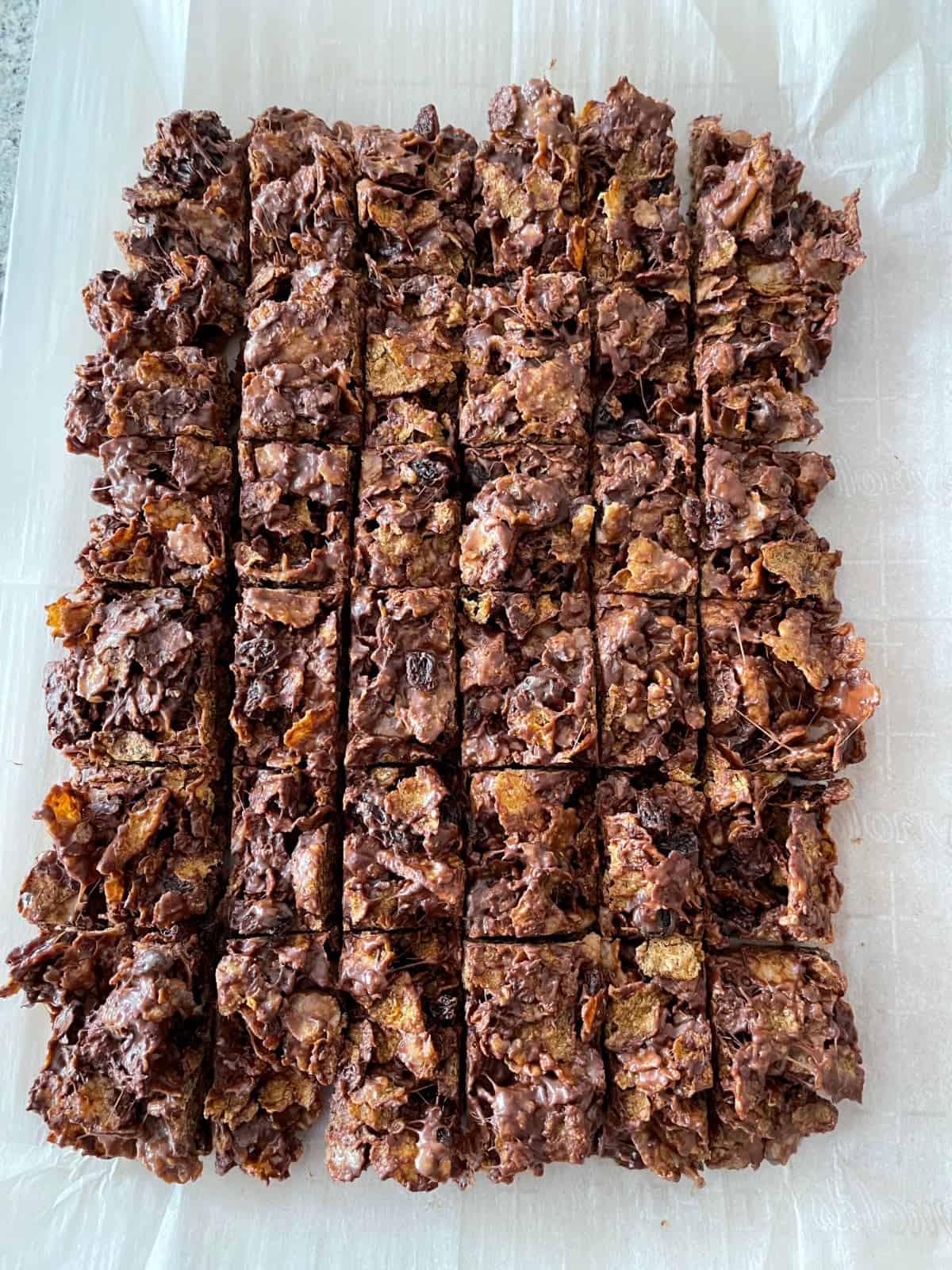 No-bake raisin bran cereal bars cut into 36 squares on parchment.